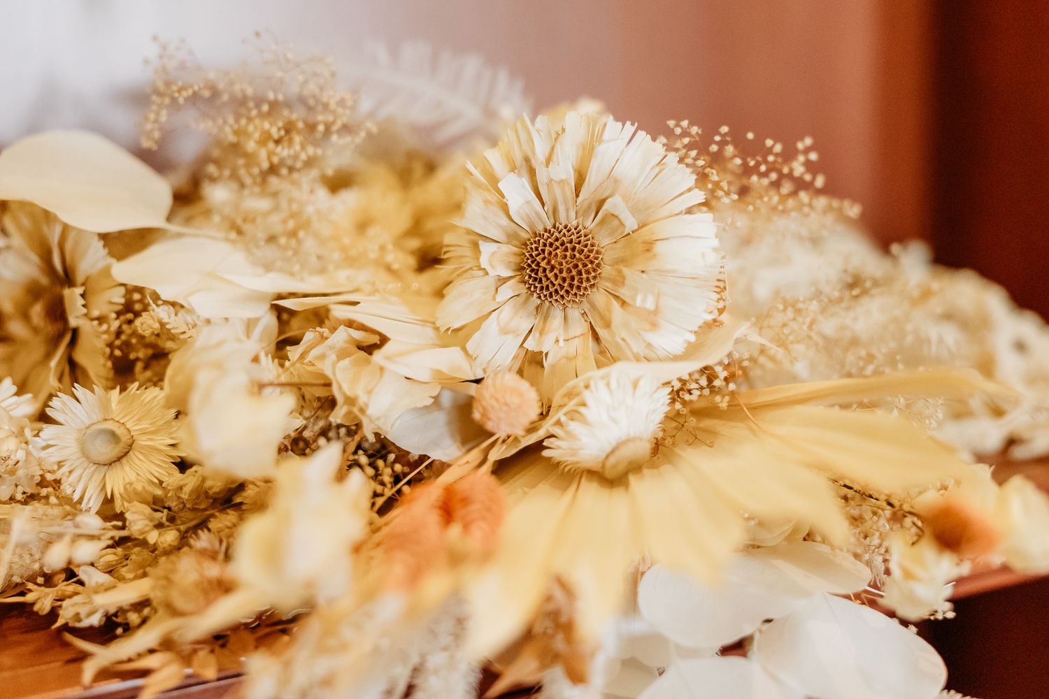 Dried floral arrangement featuring cream-colored daisies and delicate baby's breath.