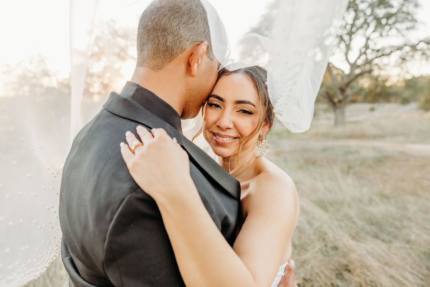 Intimate wedding moment captured during golden hour with couple embracing outdoors.