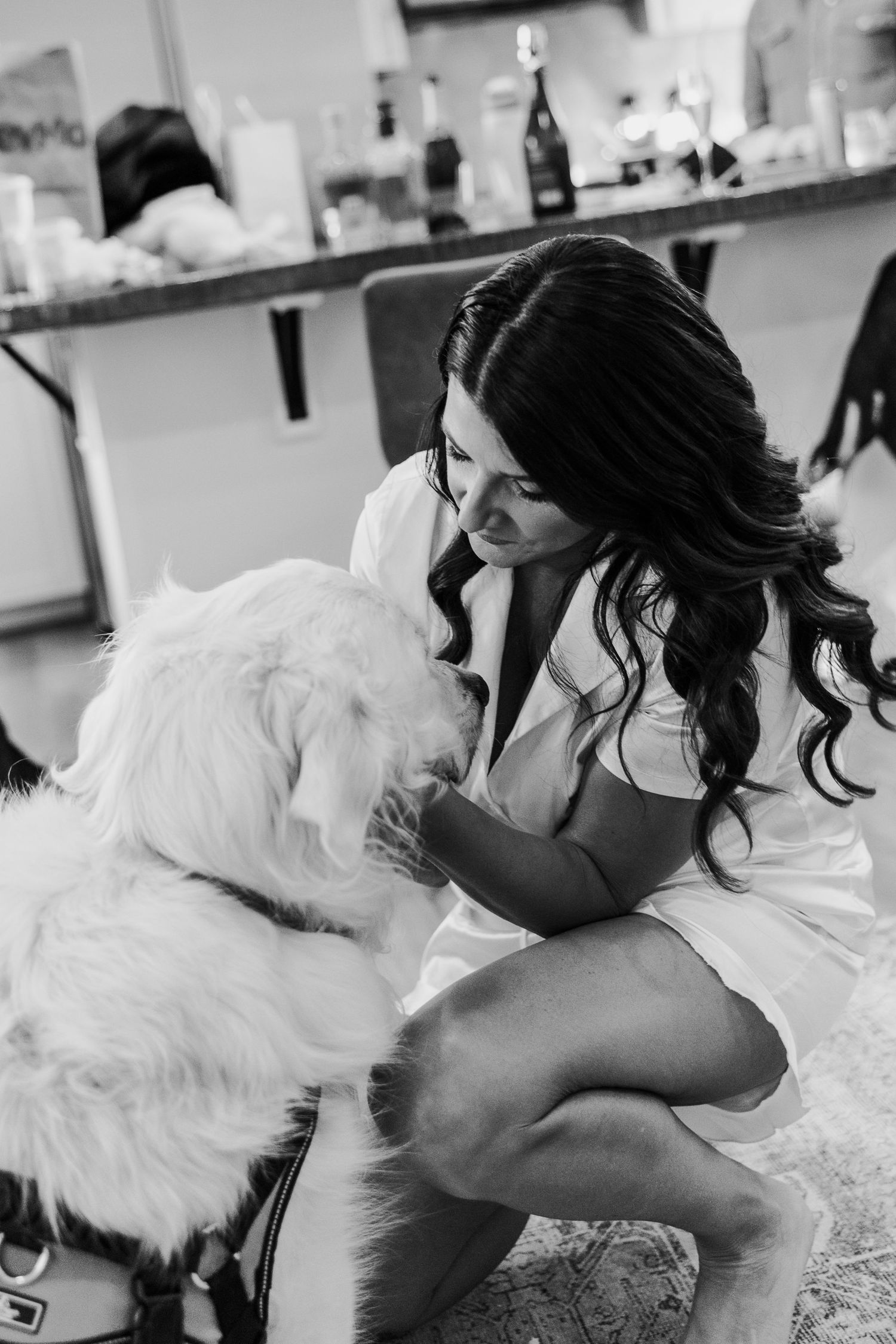 Black and white photo showing playful interaction with a fluffy white dog on a bed.