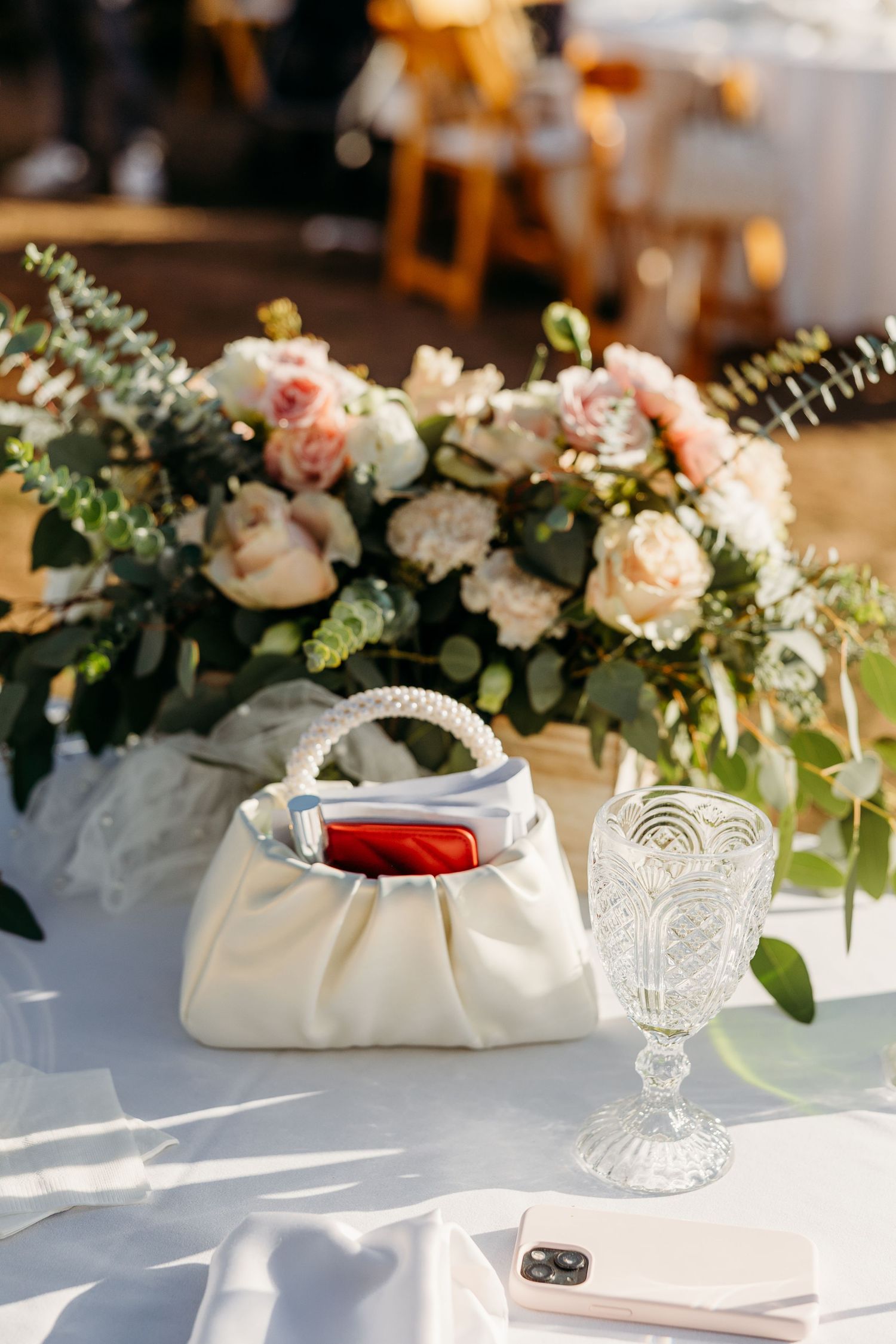 Elegant table setting with crystal glasses, white linens, and delicate floral centerpieces at wedding reception.