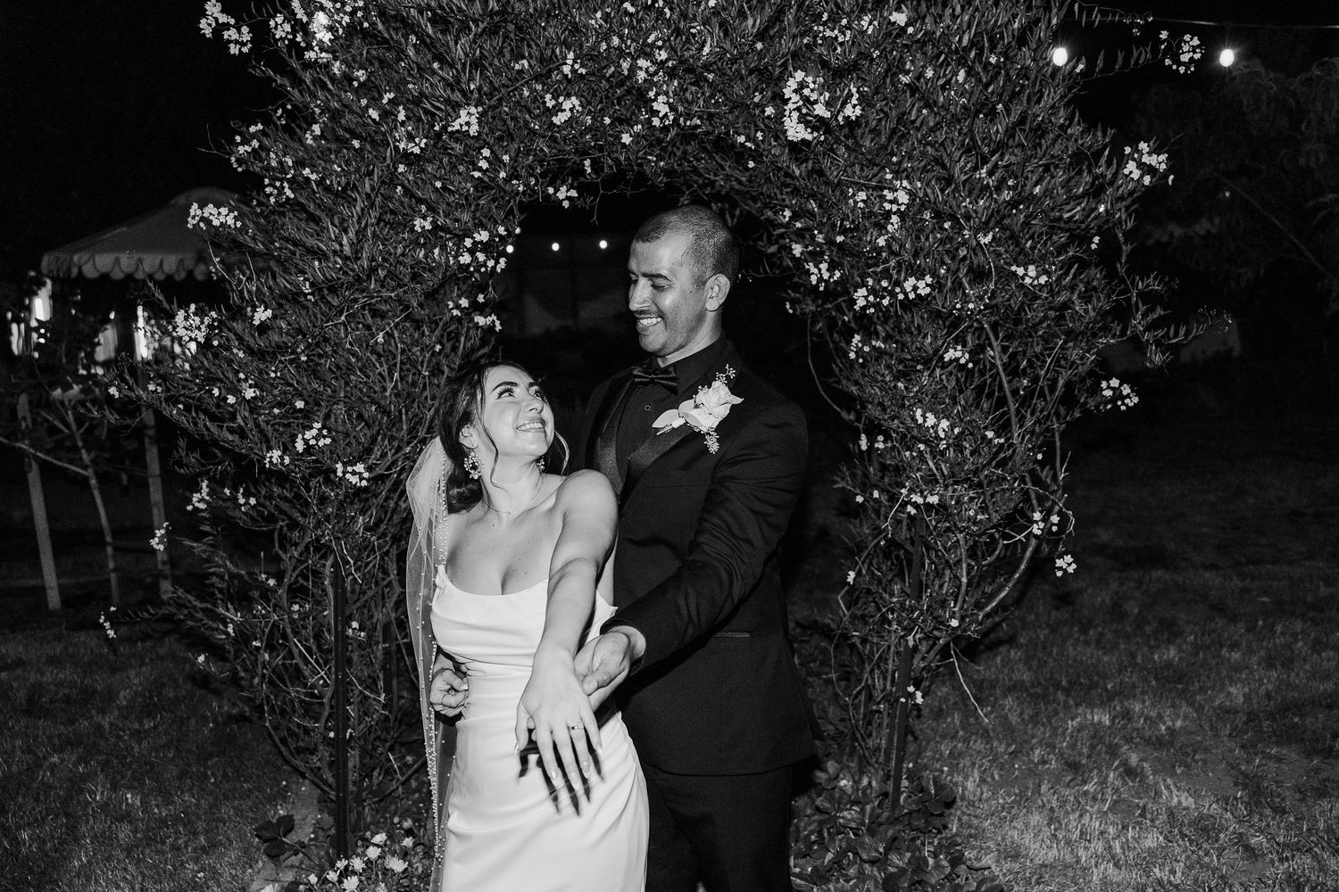 Black and white romantic wedding moment captured in an outdoor garden setting.