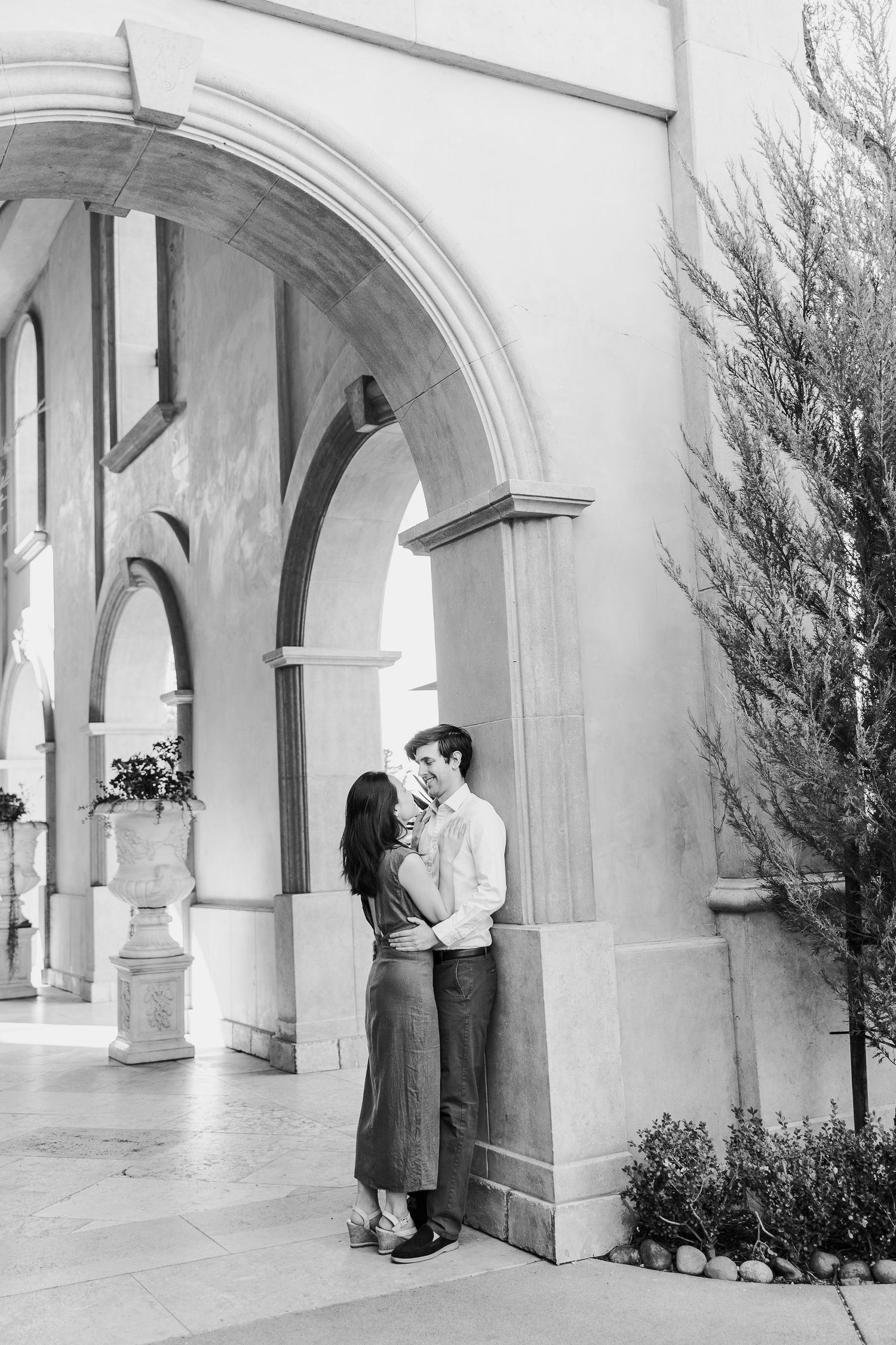 Black and white photos of a couple sharing tender moments under elegant archways.