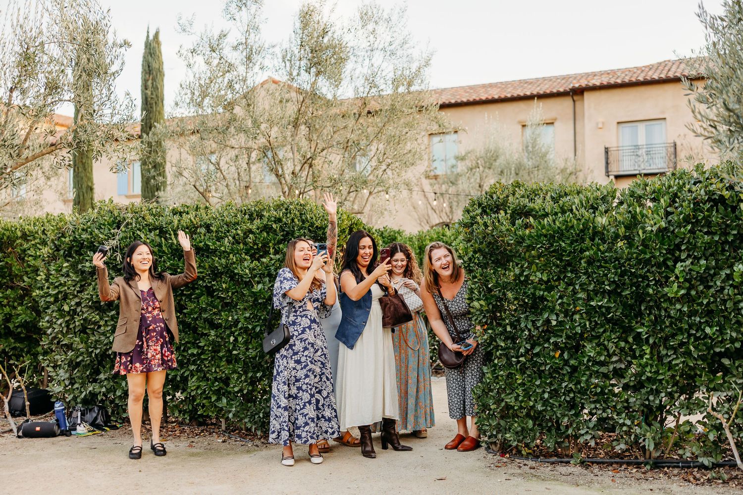 A series of outdoor family portrait shots lined up in a row showing people posing against a garden hedge backdrop.