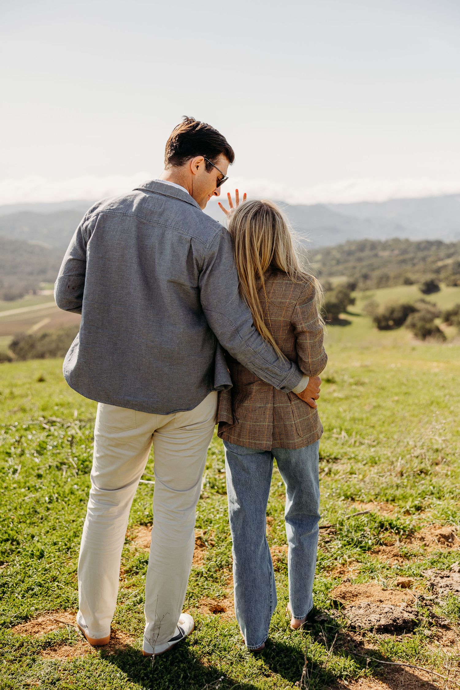 Couple embracing while enjoying scenic mountain views in casual winter attire.