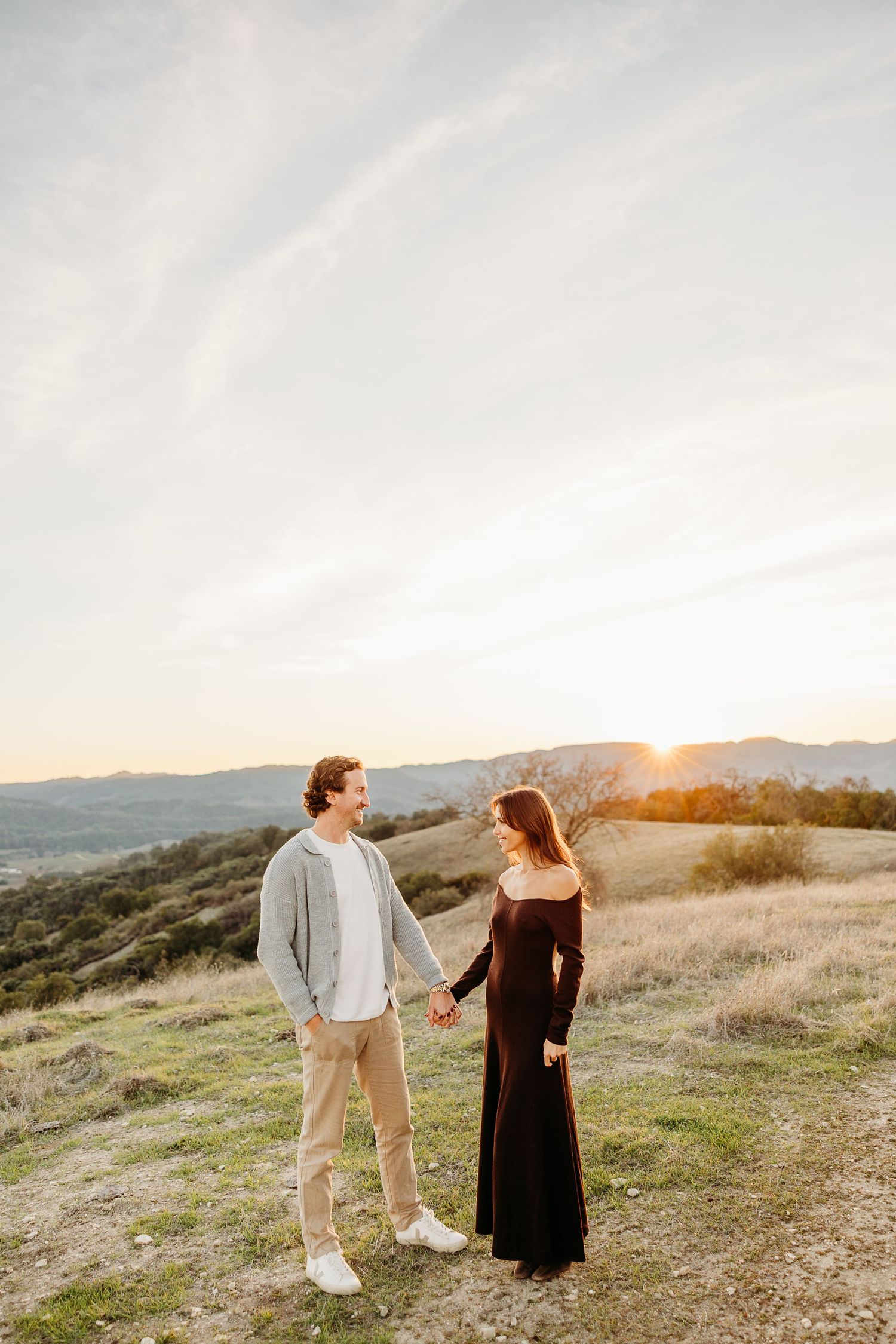 Couple walking together on hilltop trail during golden hour.