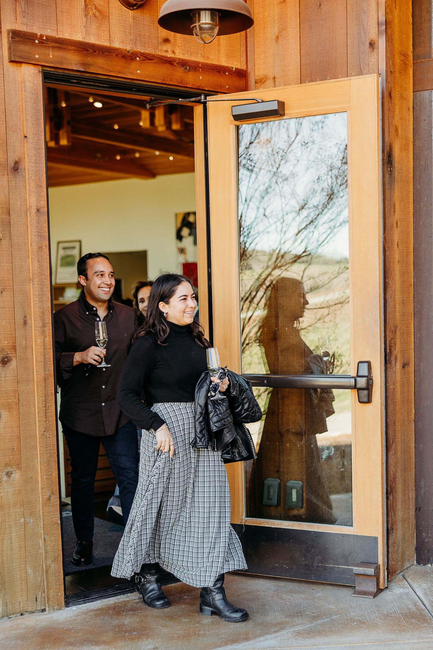 People walking through a rustic wooden entrance with glass doors at what appears to be a mountain lodge or cabin.