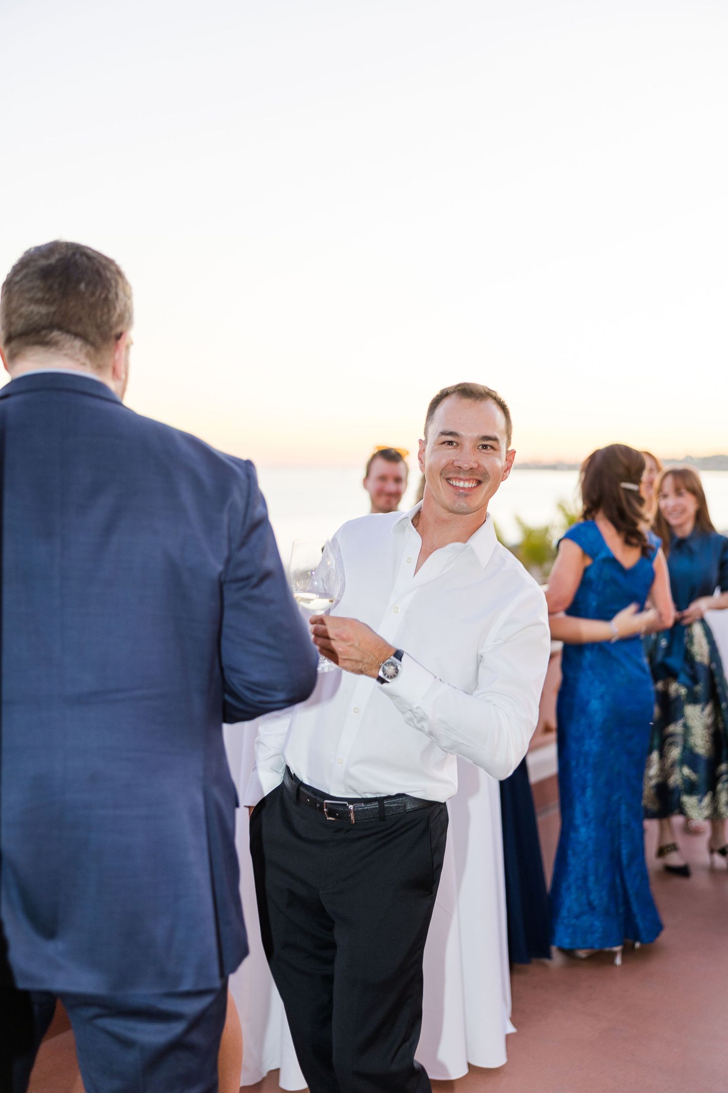 Wedding guests socializing during an outdoor reception with sunset lighting.