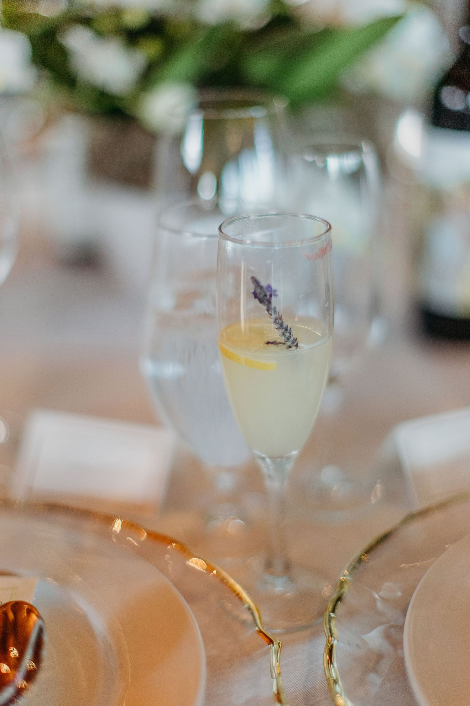Wedding reception drinks garnished with lavender sprigs and lemon slices in crystal glasses.