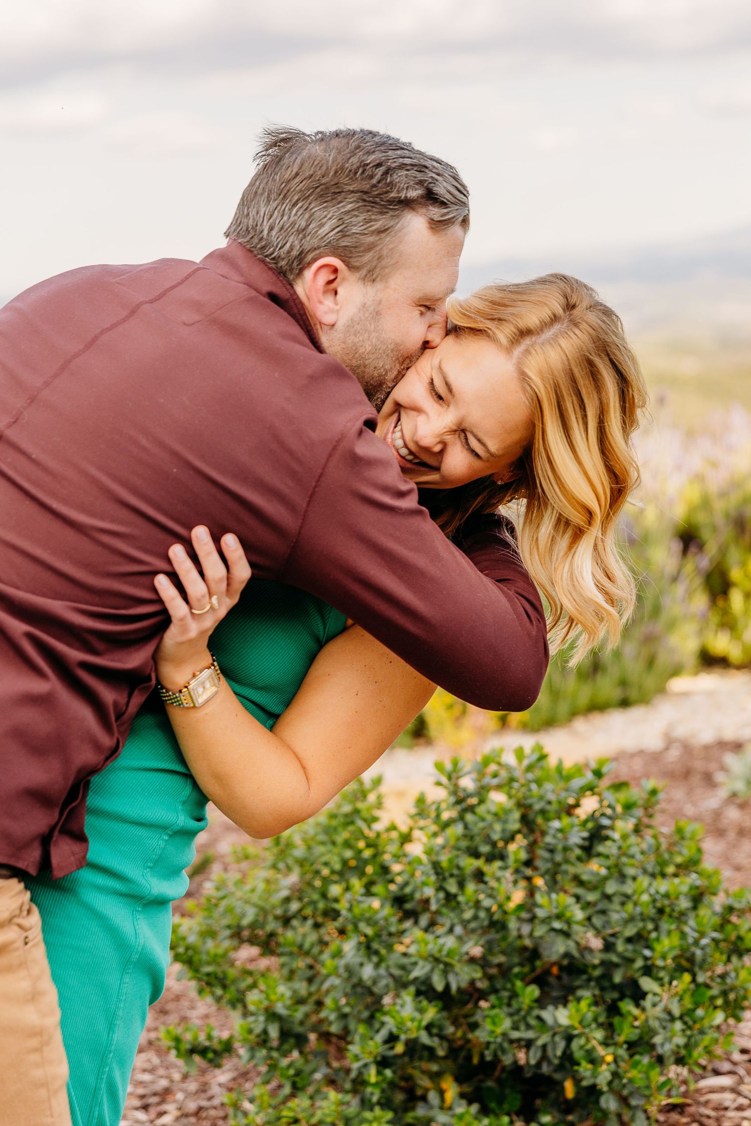 A romantic moment captured between a couple embracing in a garden setting with blooming flowers.