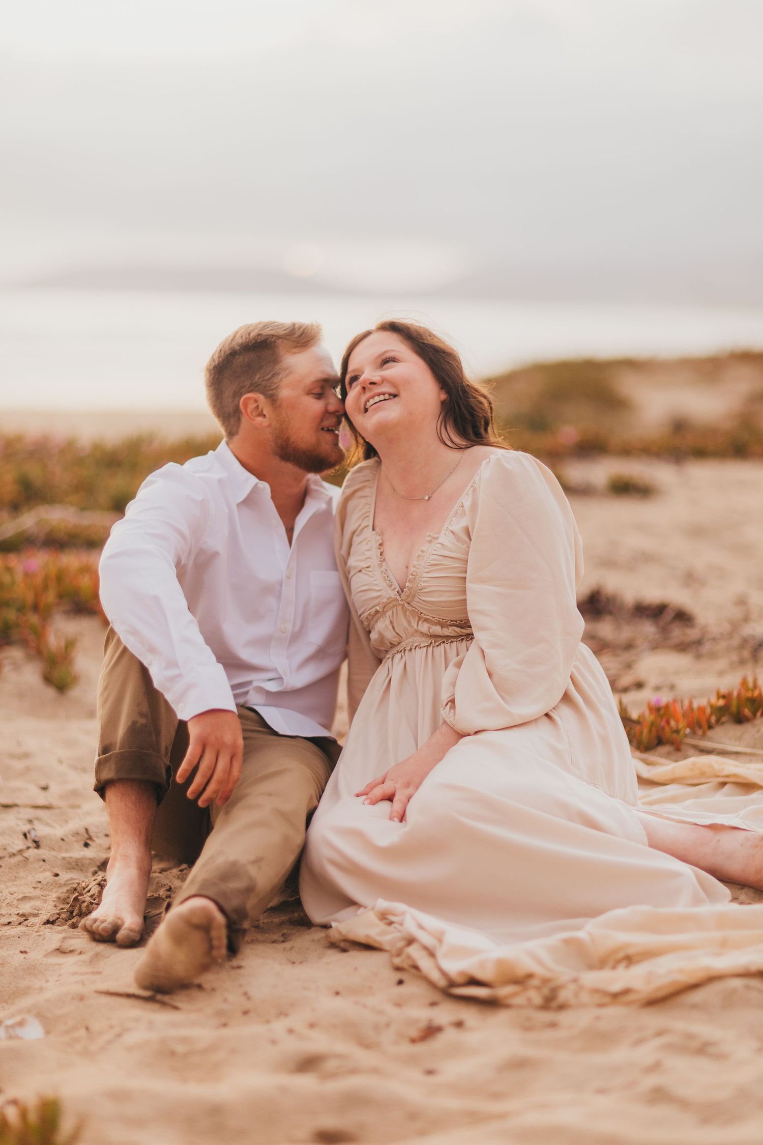 Romantic couple sharing a joyful moment together on a sandy beach at sunset.
