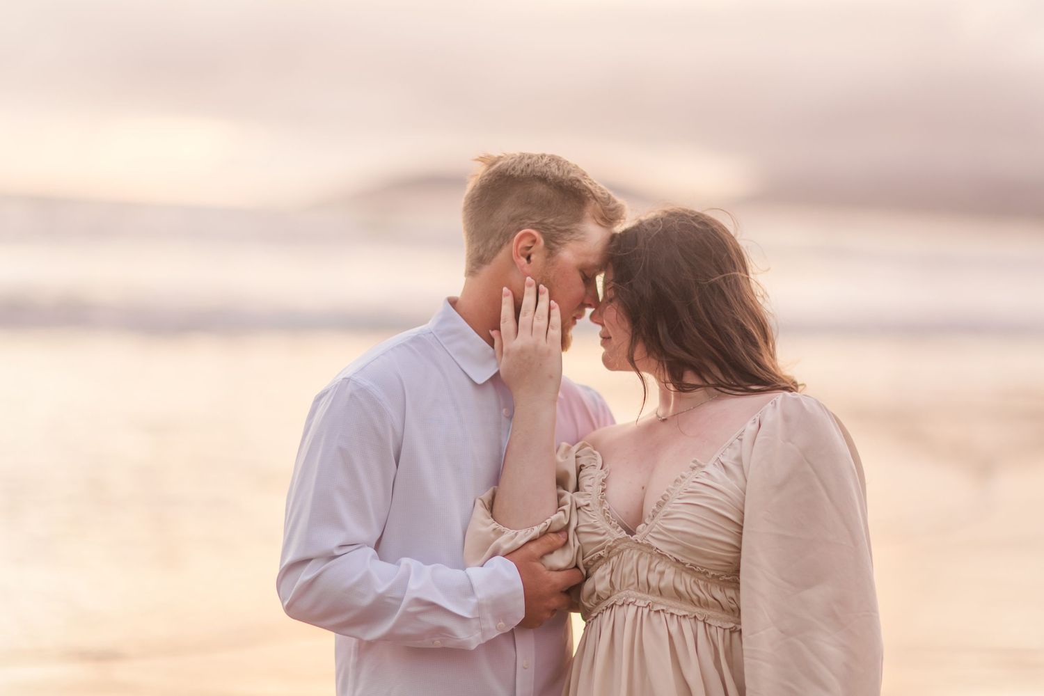 An intimate moment captured between a couple on the beach during golden hour.