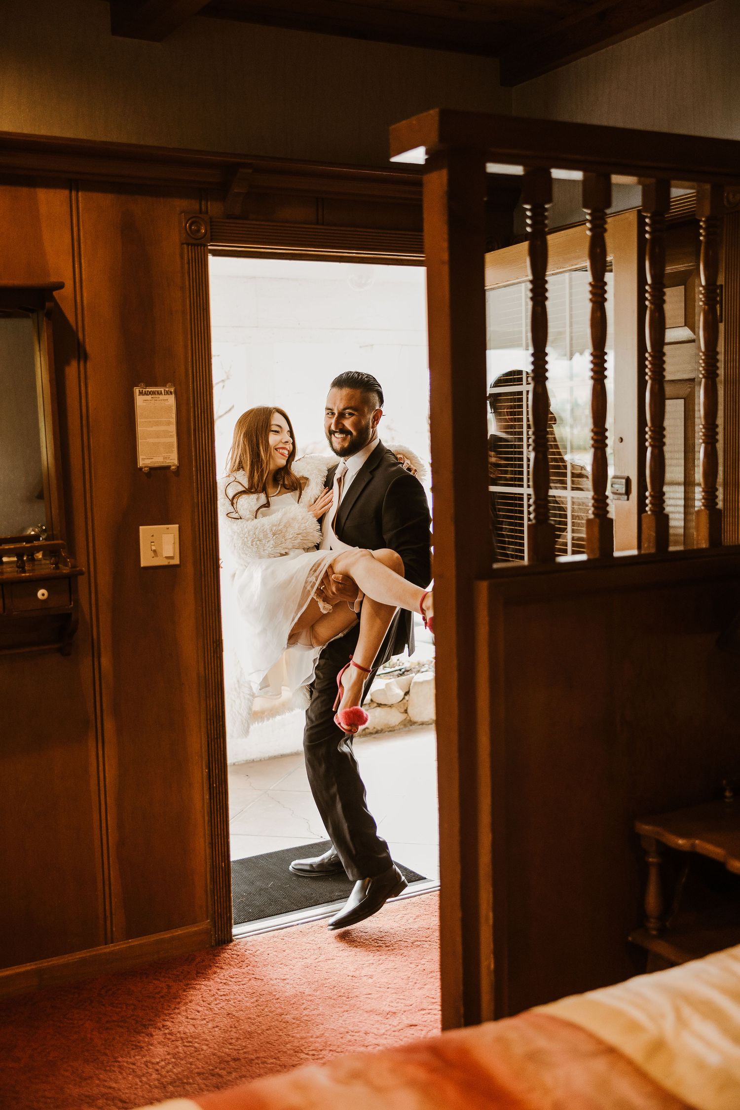 A couple entering through a wooden doorway in a rustic venue with warm lighting and vintage-style interior details.