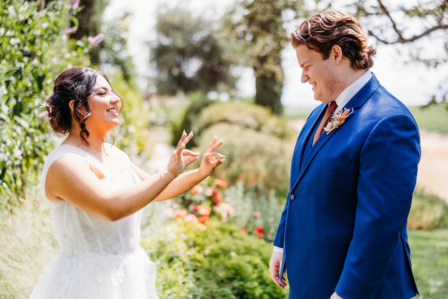 Wedding couple shares an animated moment in a garden setting.