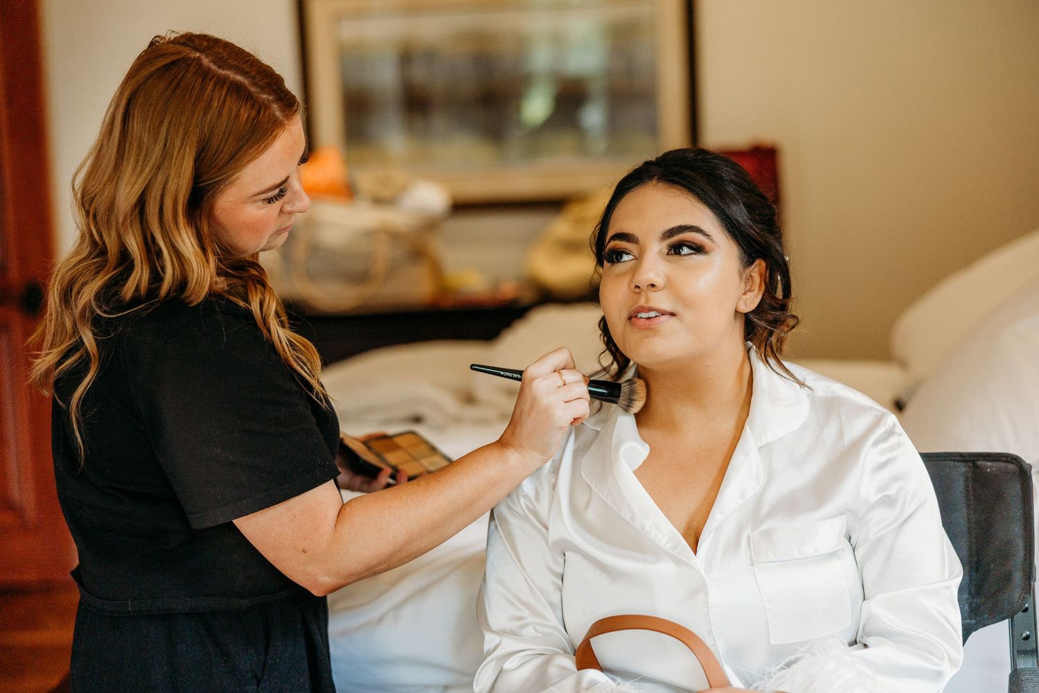 Professional makeup artist applying cosmetics during wedding preparation.