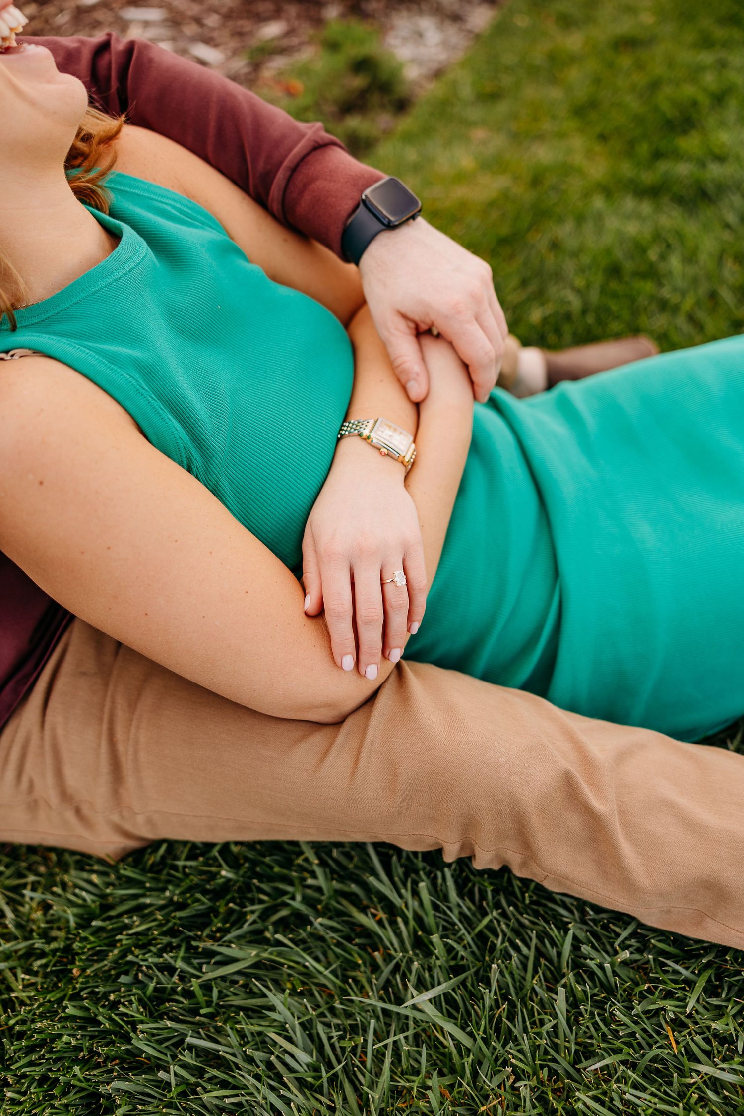 Close-up of person wearing green dress and khaki pants lying on grass in outdoor setting.