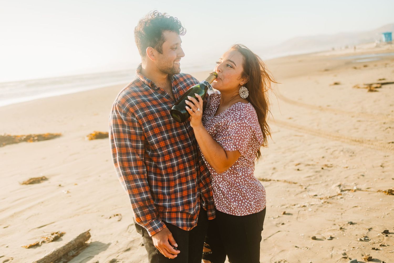 A couple shares a joyful moment together on a sandy beach.