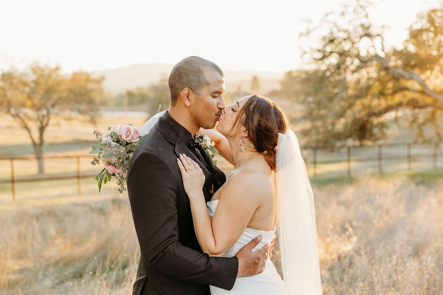 A sunset wedding portrait captures an intimate moment between newlyweds in a golden field.