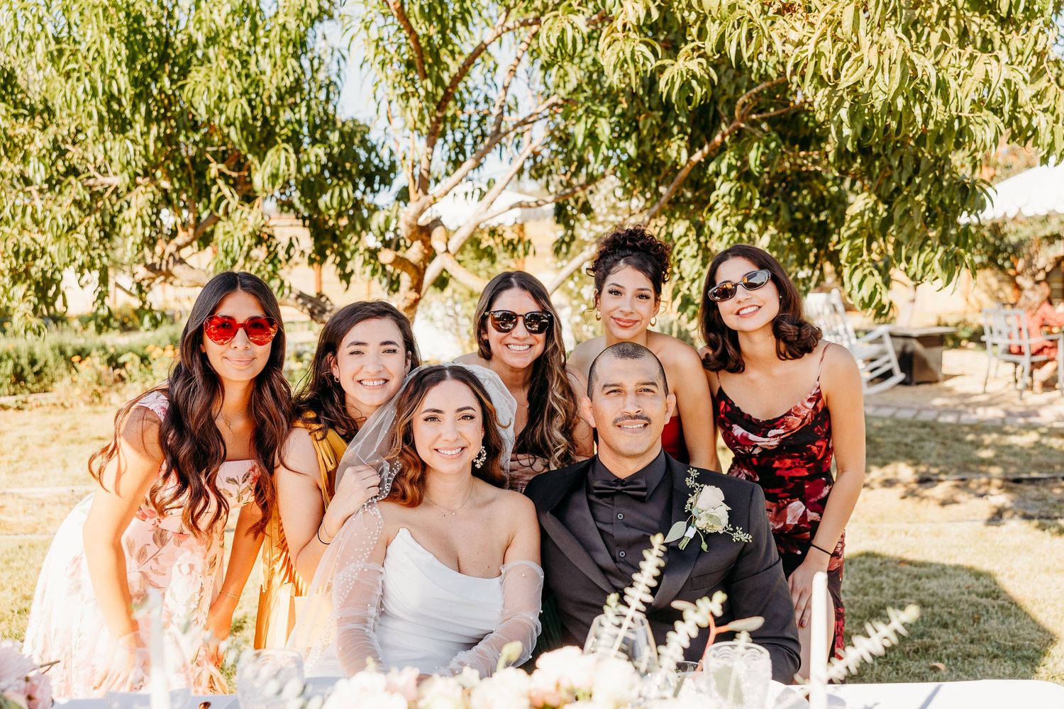 Wedding guests smiling and celebrating outdoors on a sunny day.