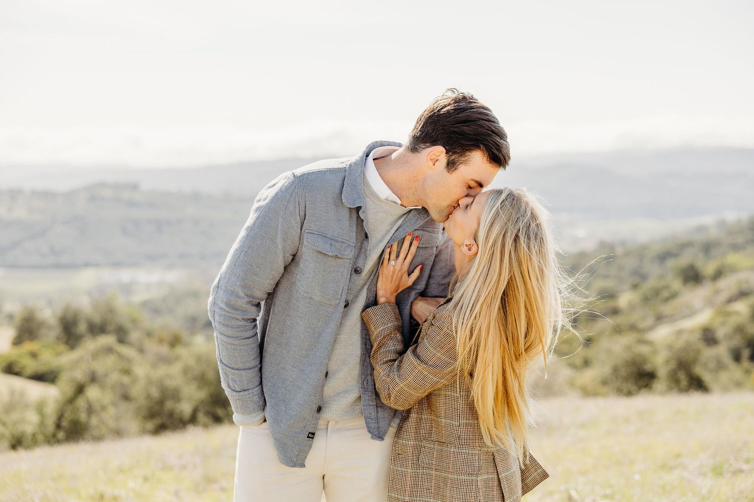 Tender moment captured between couple in golden afternoon light on hillside.