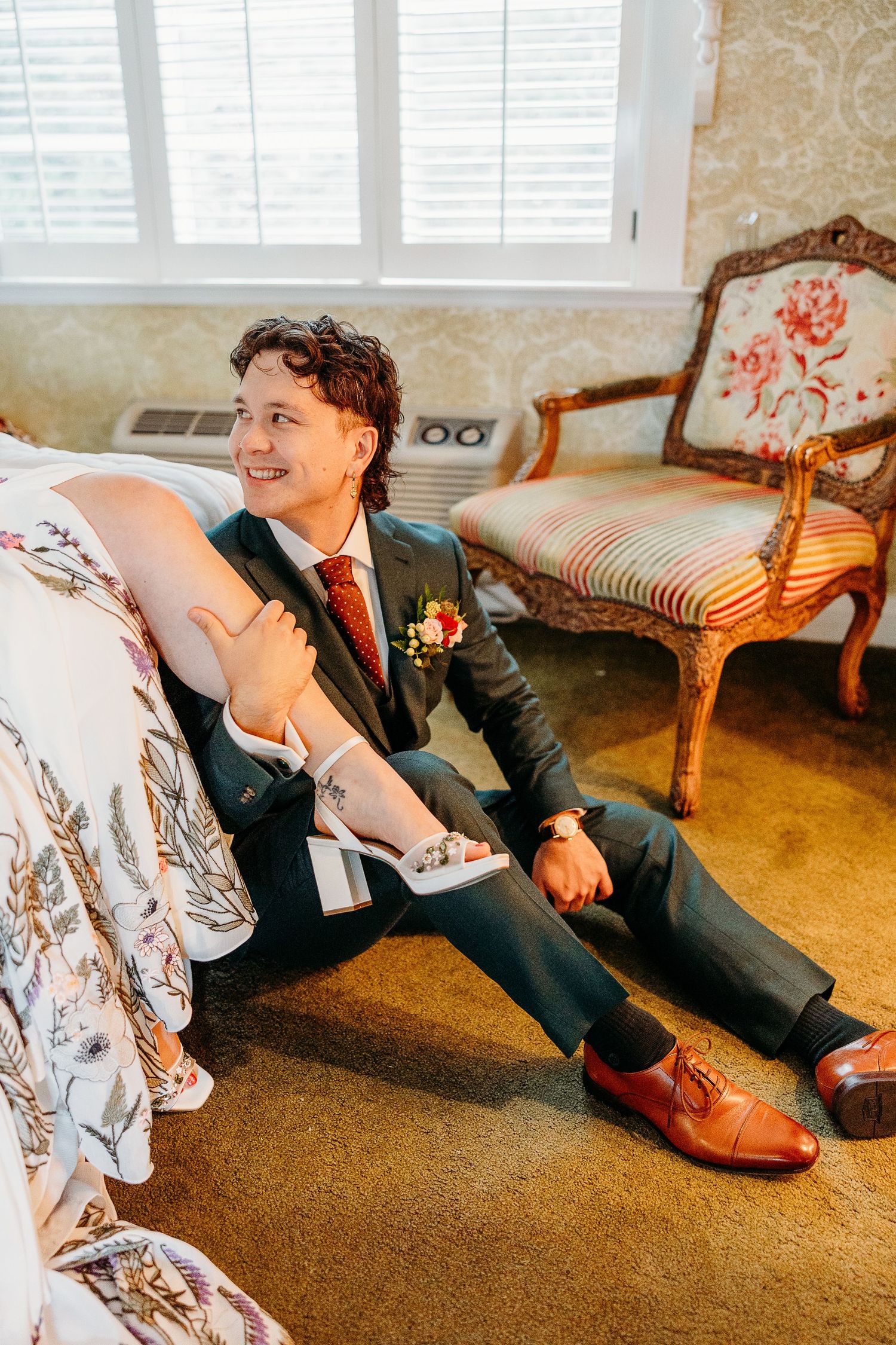 Playful wedding photos taken on the floor showing formal attire and candid moments.
