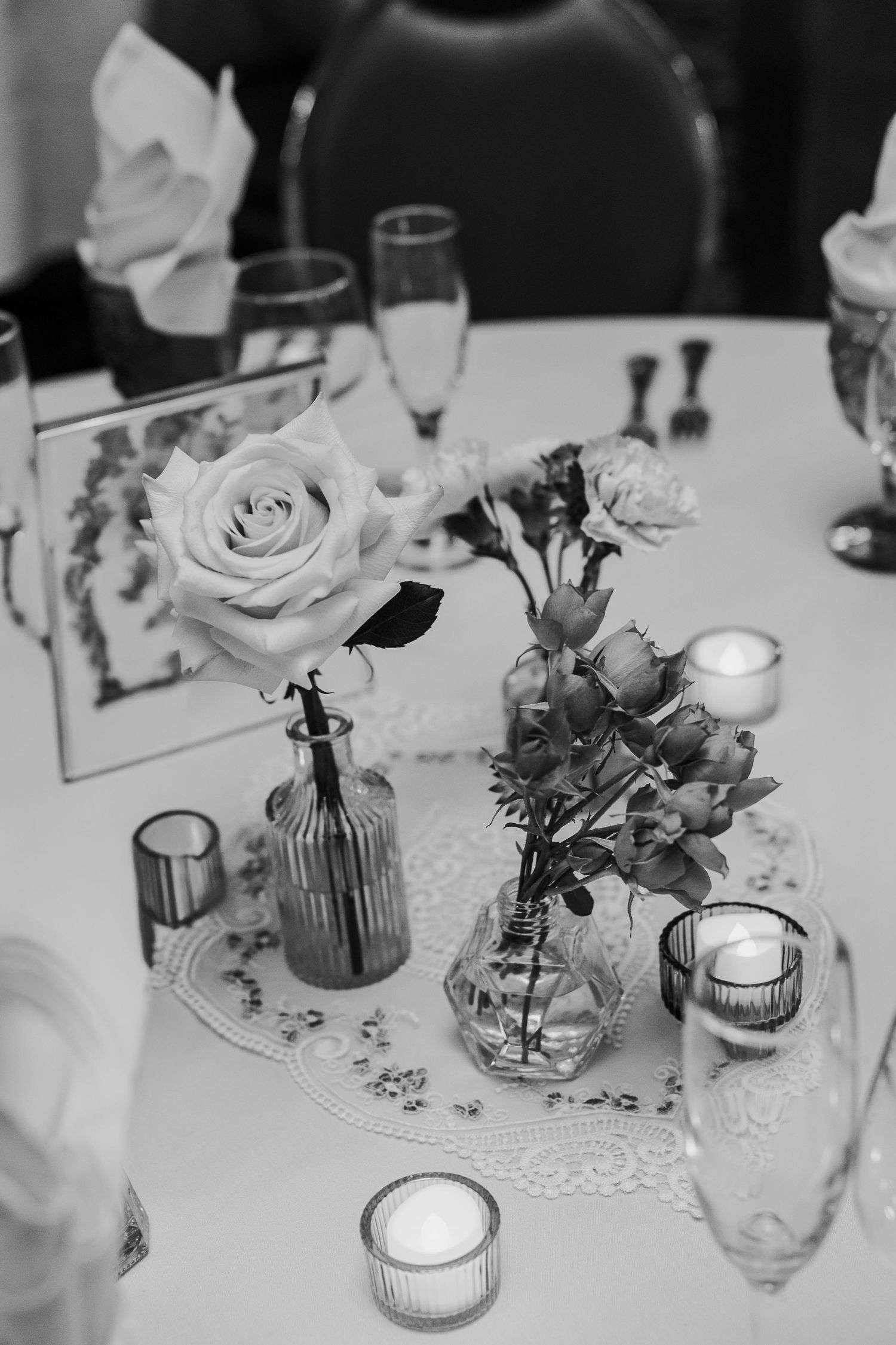 Elegant wedding reception table settings with white linens, candles, and floral centerpieces.