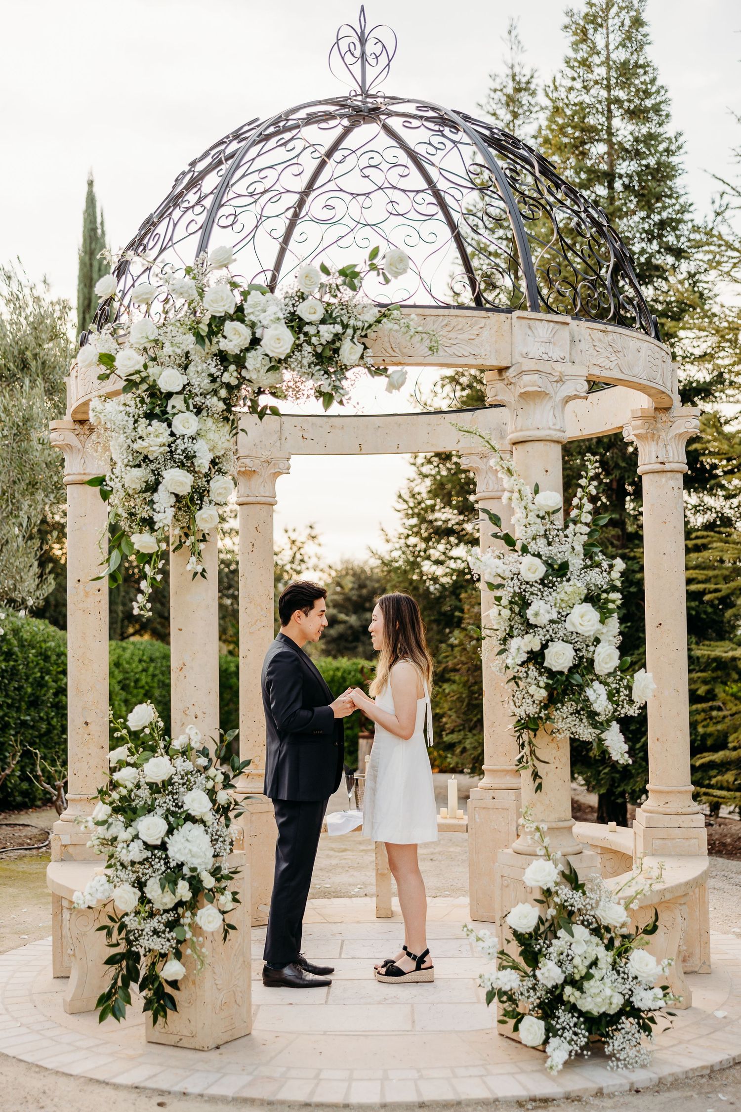 Elegant gazebo decorated with white floral arrangements and greenery for a romantic occasion.