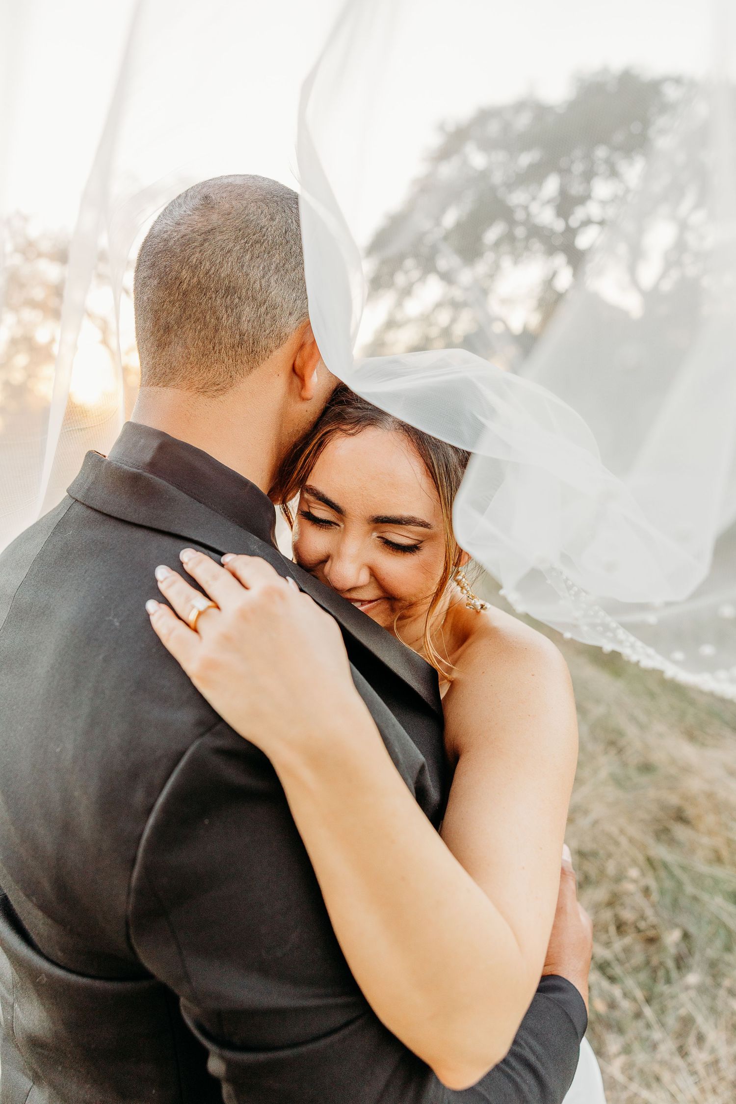 Intimate wedding couple embracing during sunset portraits in a natural outdoor setting.