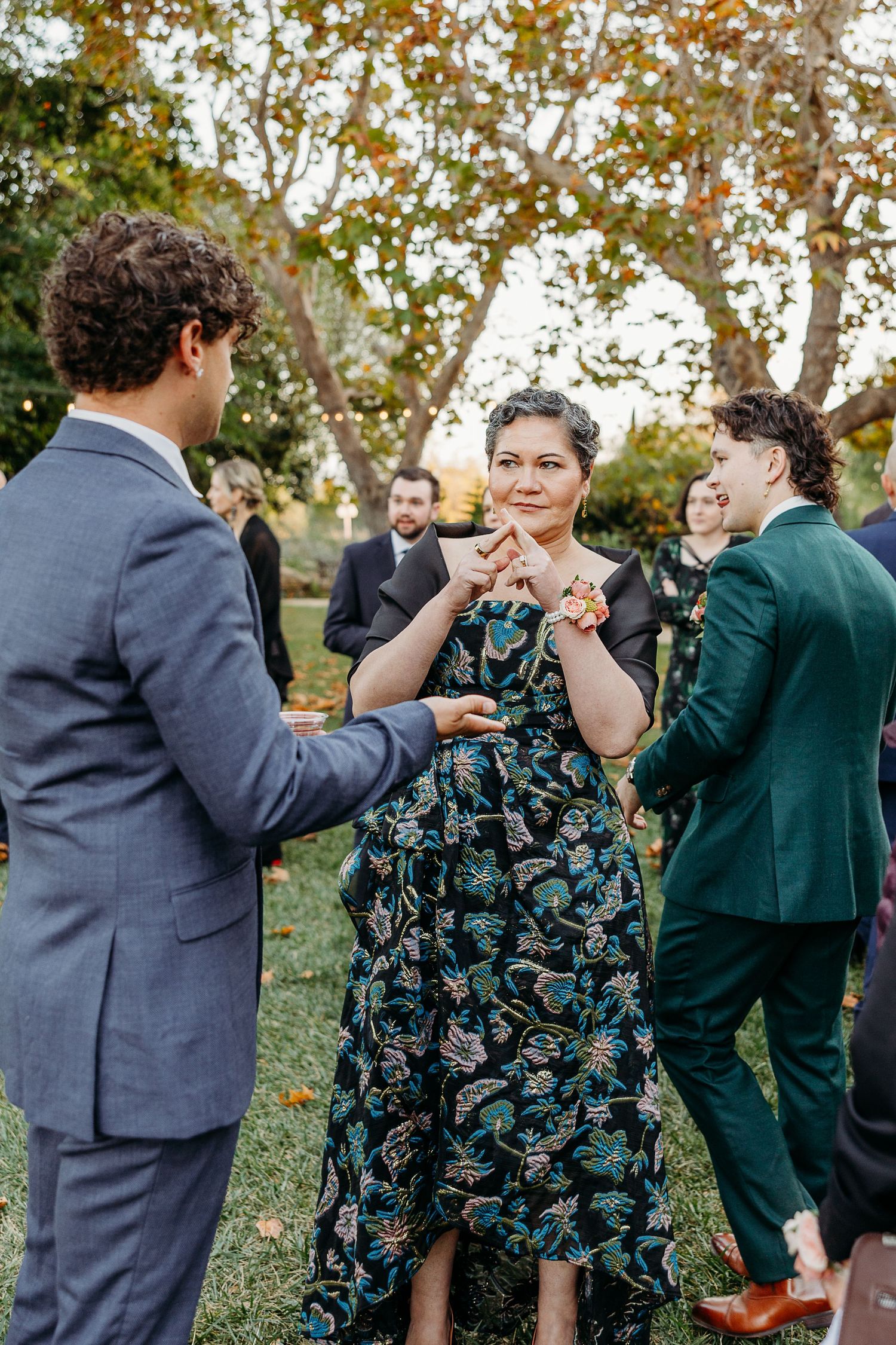 Wedding guests dancing and celebrating outdoors in formal attire.