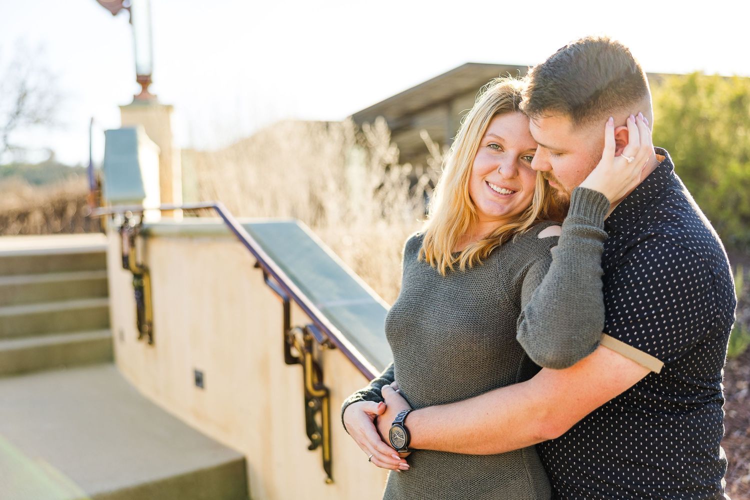 Couple embracing on outdoor steps during a sunny afternoon.