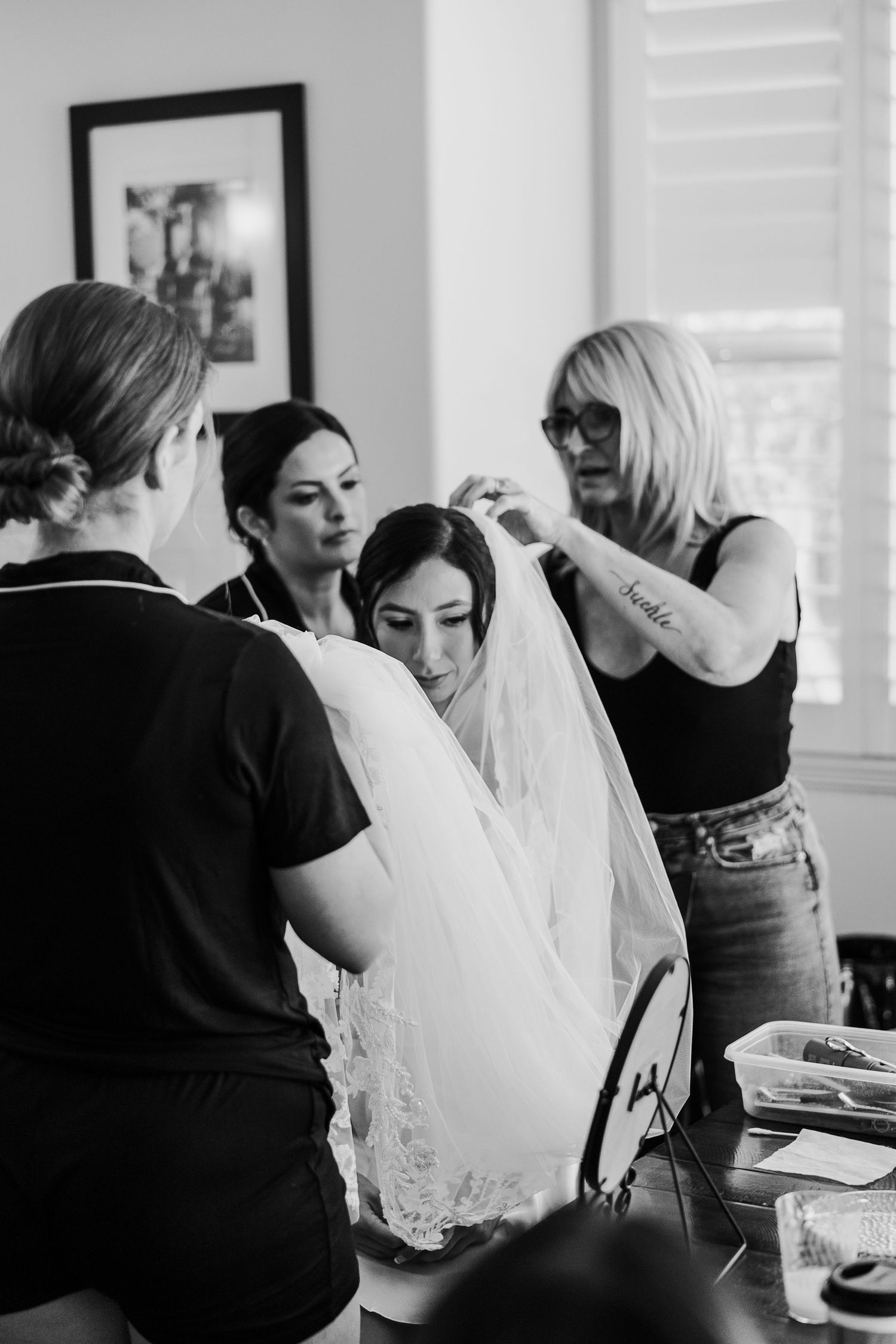 Black and white photo series showing wedding preparation moments with a flowing white veil in focus.