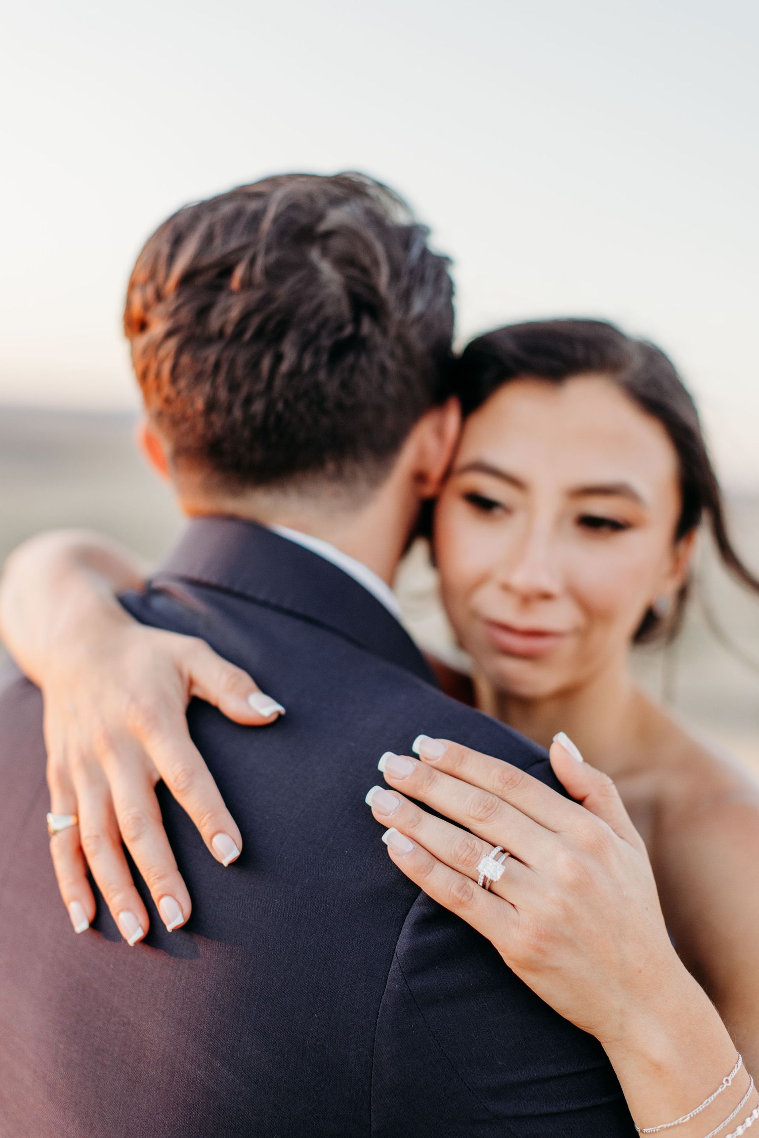 Close-up of engagement ring and embrace during sunset photoshoot.