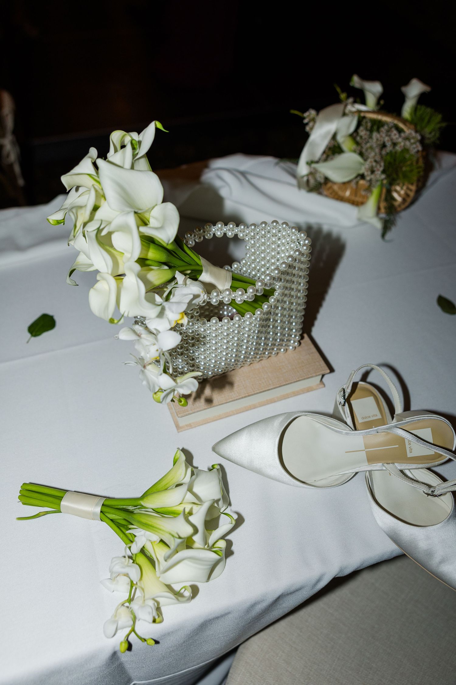 Elegant white calla lily bouquets and pearl decorations arranged on a reception table.