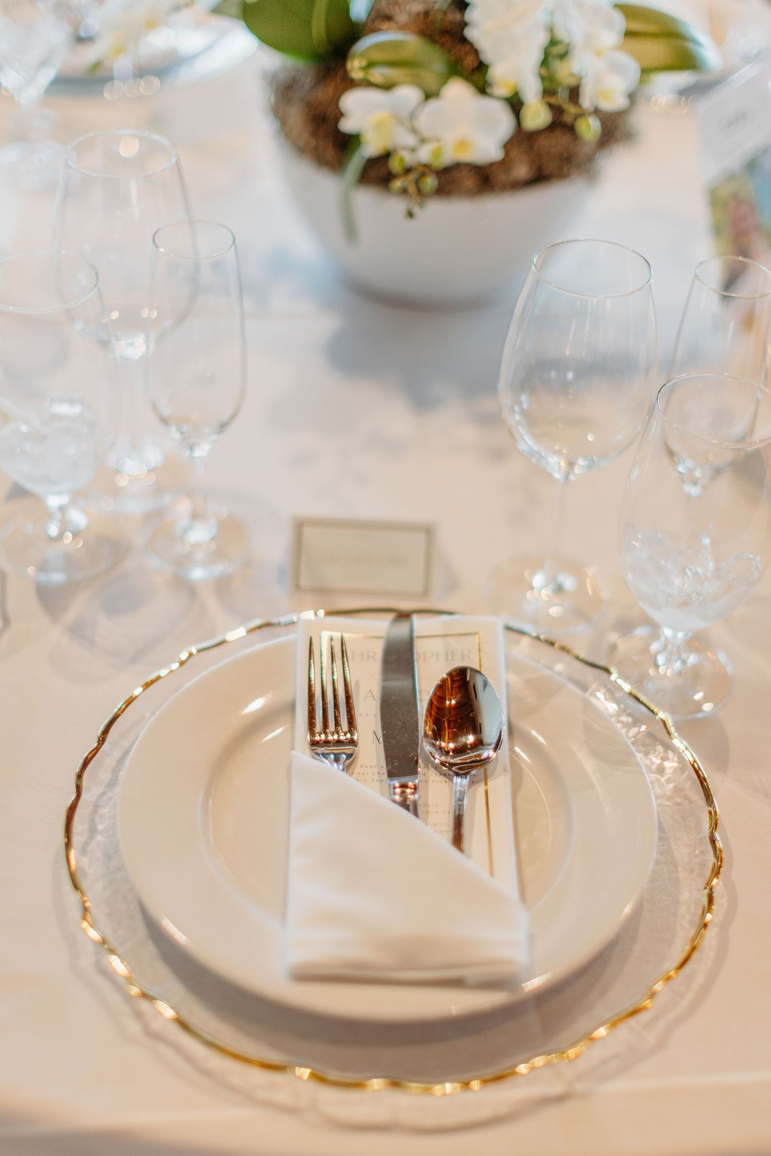 Elegant place settings with gold-rimmed plates and crystal glasses on a white tablecloth.