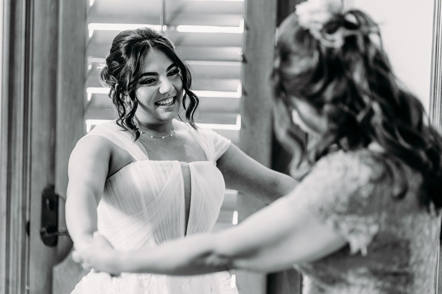 A black and white candid moment showing genuine emotion and connection during wedding preparations.