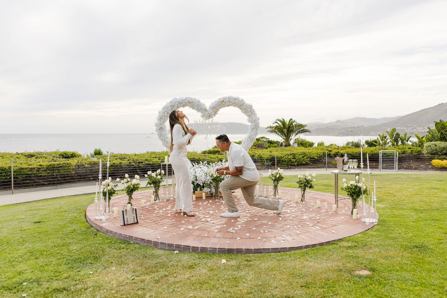 A romantic couple embraces outside a rustic doorway with stone walls and wine barrel decoration.