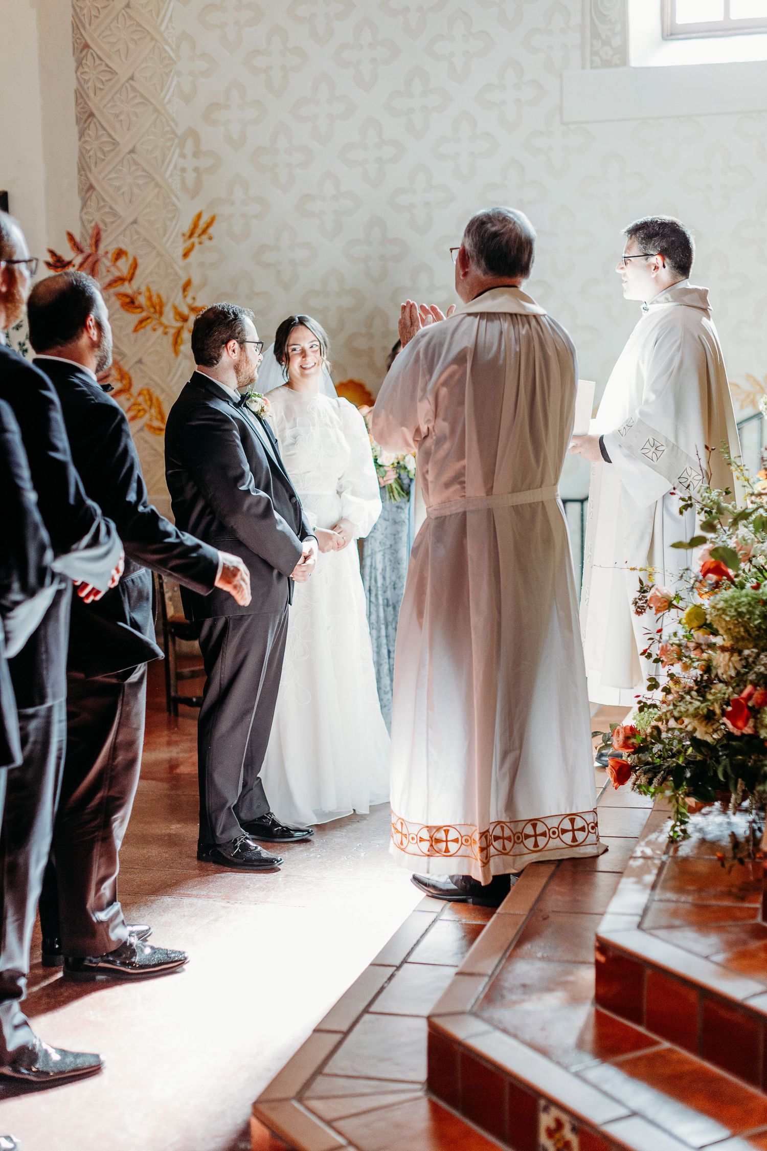 Religious wedding ceremony in progress with clergy and guests in ornate church interior inside of the San Luis Mission.