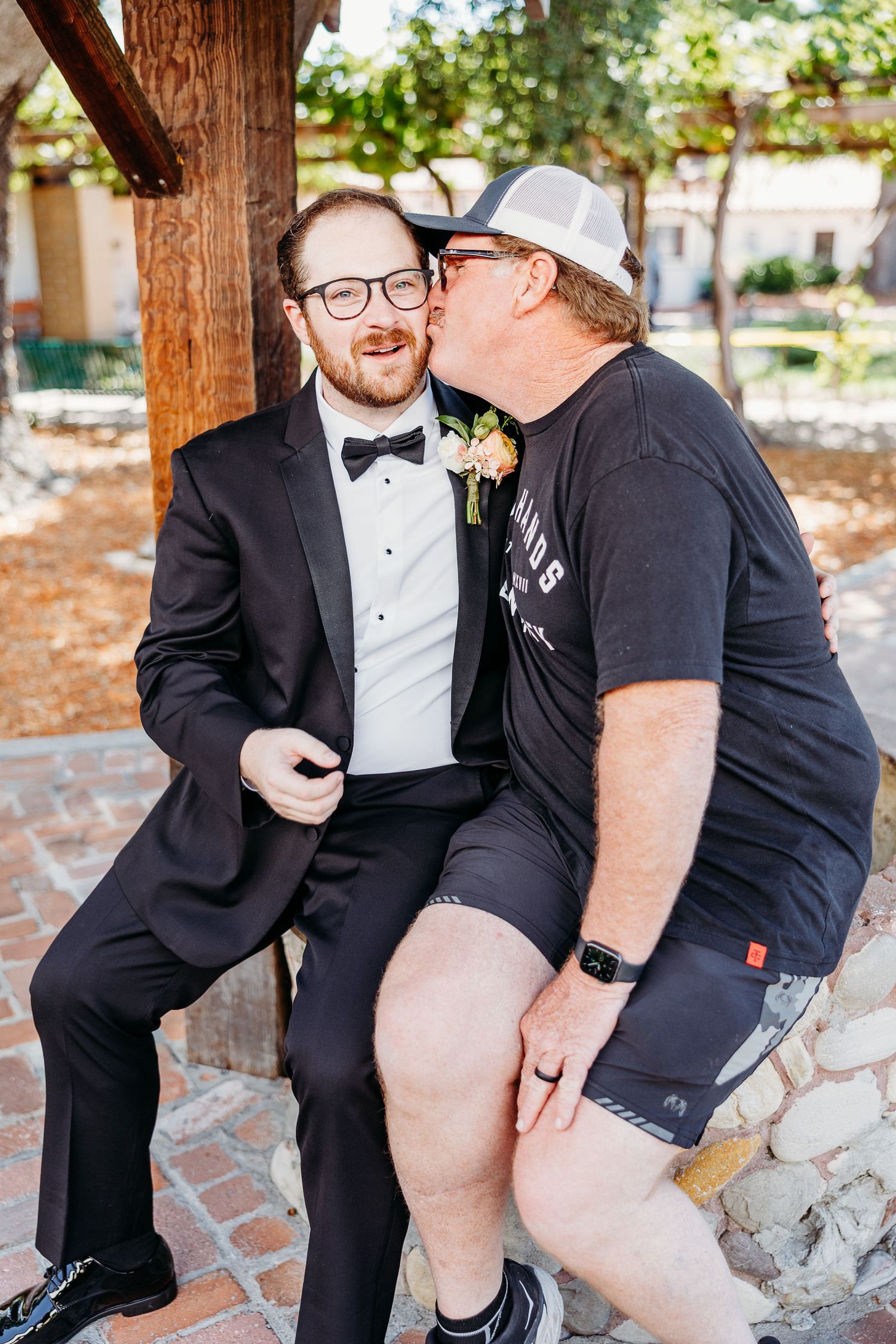Two wedding guests sharing a candid moment on a stone bench.