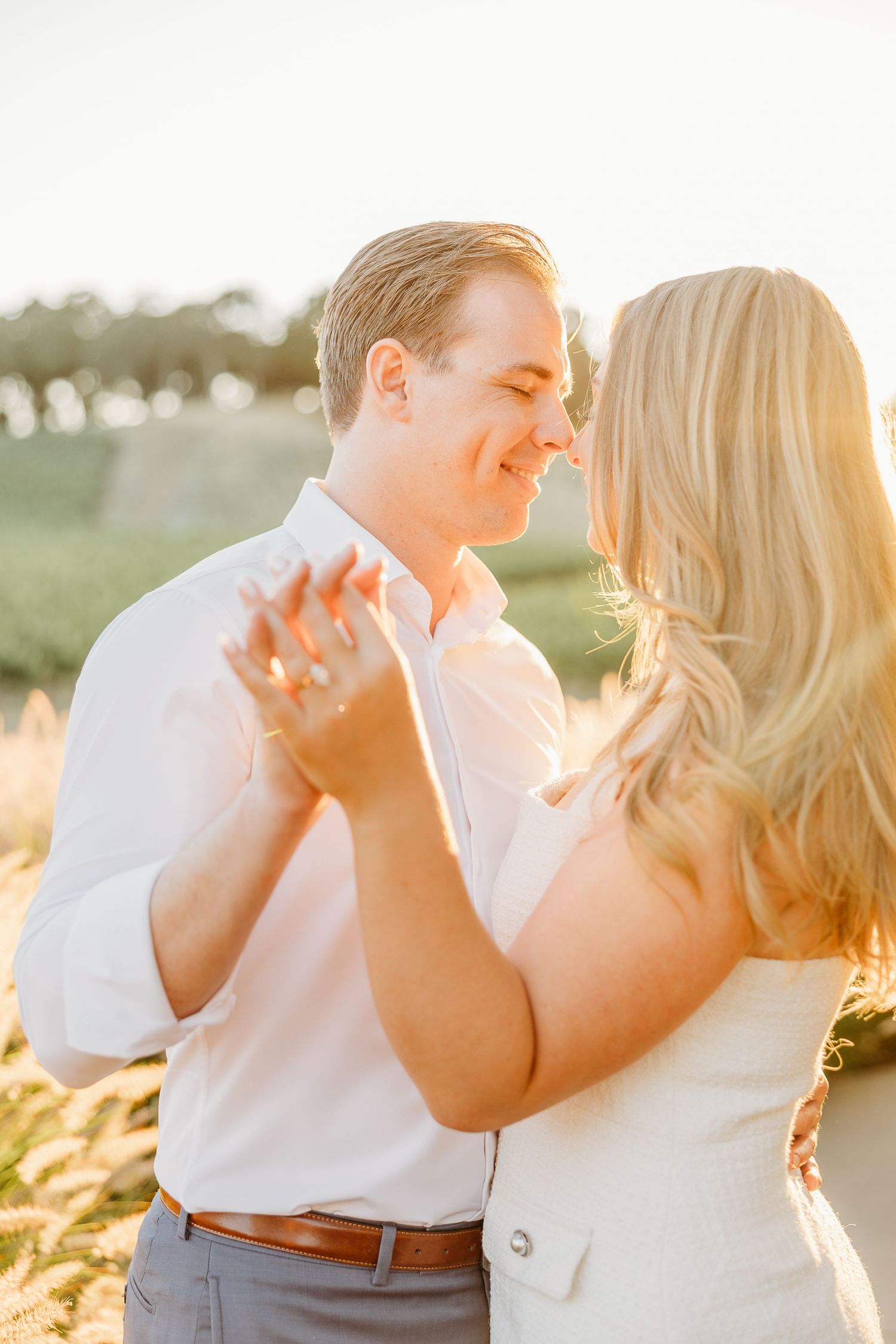 Couple shares intimate moment in golden sunlight during sunset engagement session.