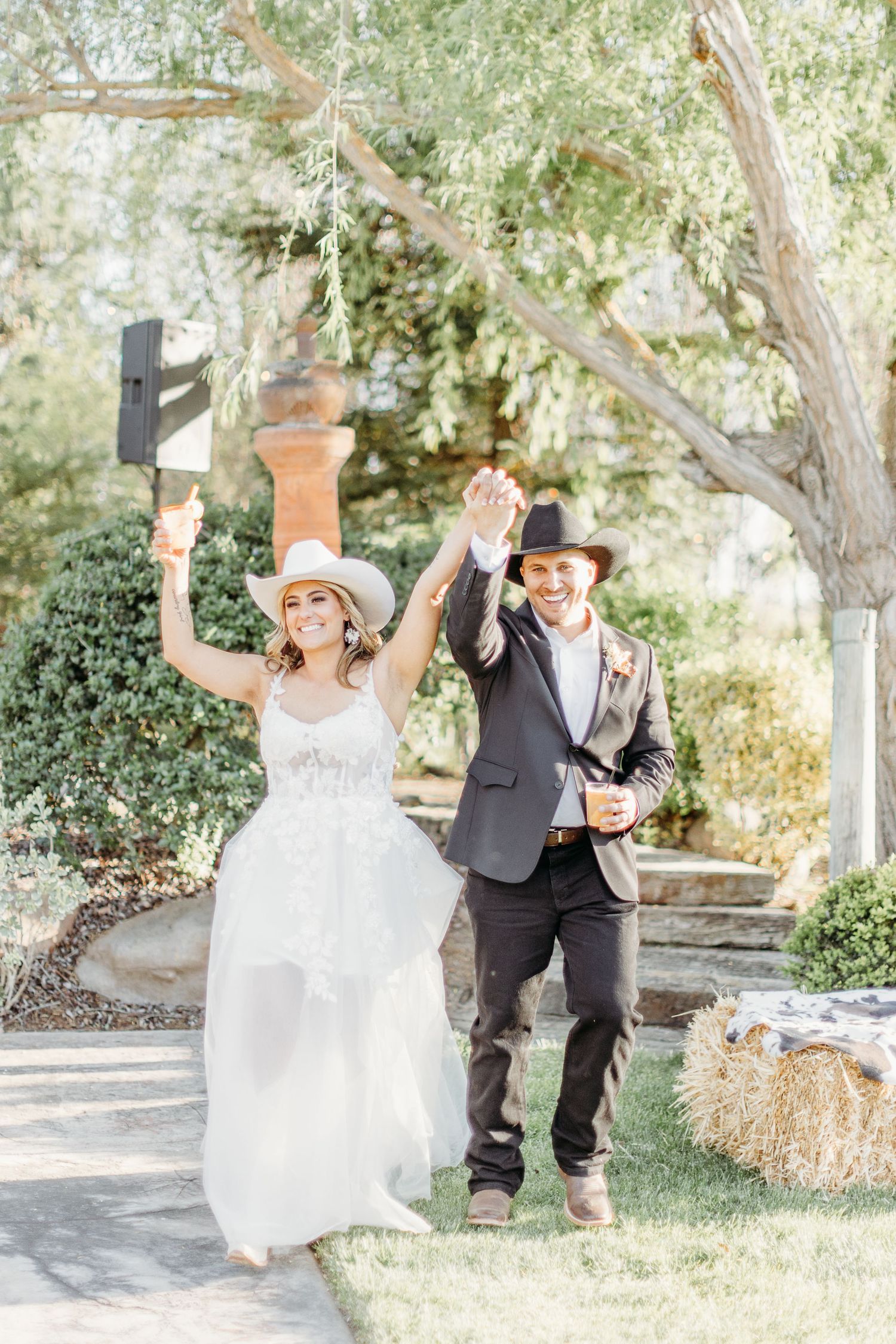 A western-themed wedding couple celebrates joyfully on their special day in an outdoor garden setting.