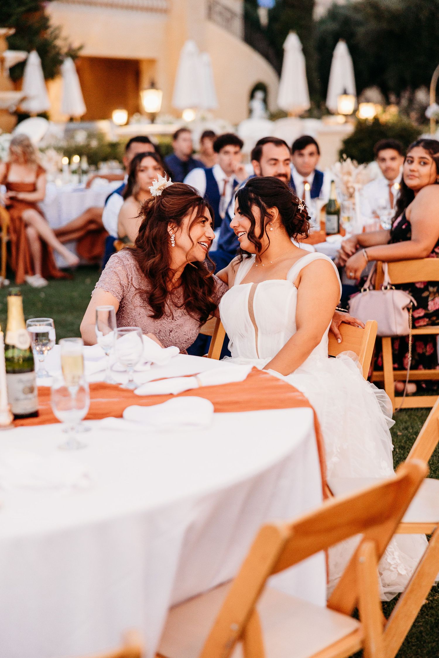 Wedding guests enjoy an outdoor reception dinner at decorated tables.