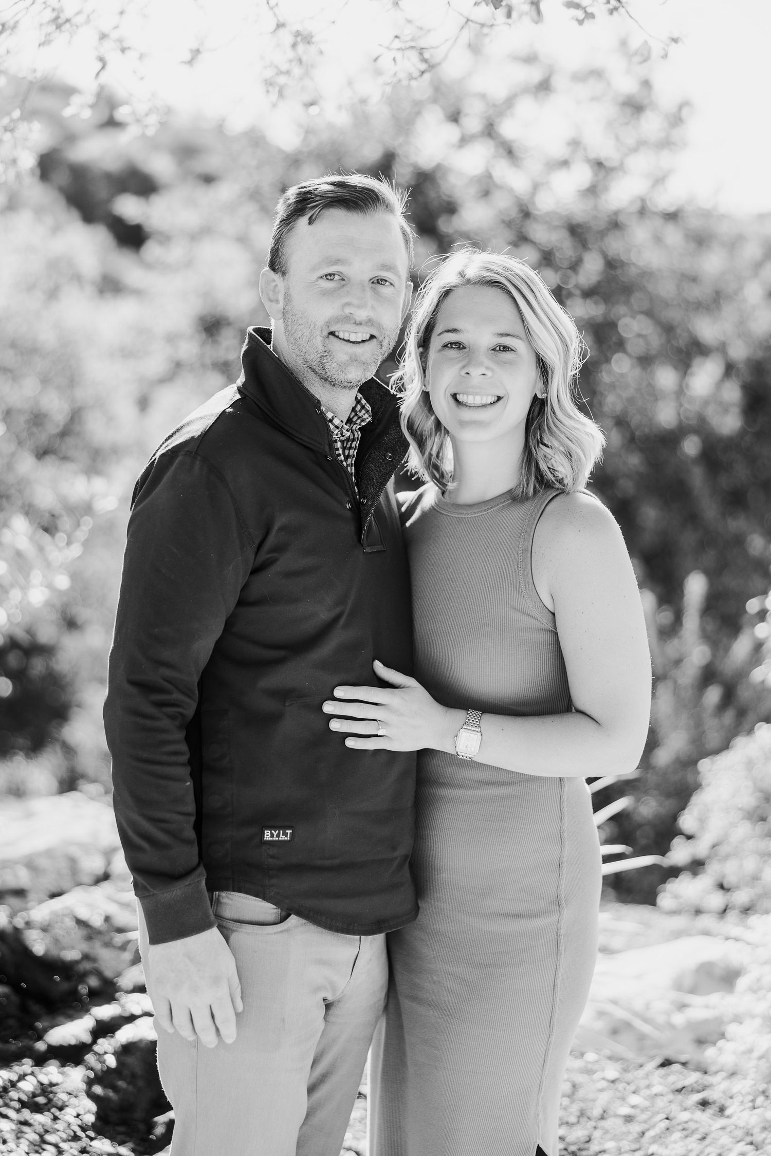 A couple poses together outdoors in black and white photos showing joyful candid moments.