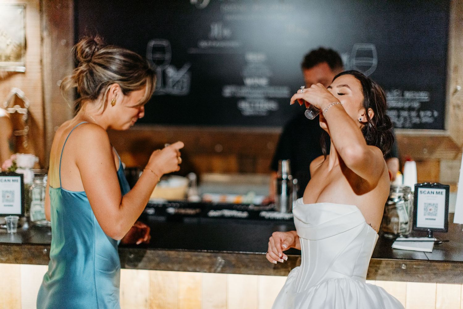 Wedding reception guests enjoying drinks and conversation at a rustic barn venue.