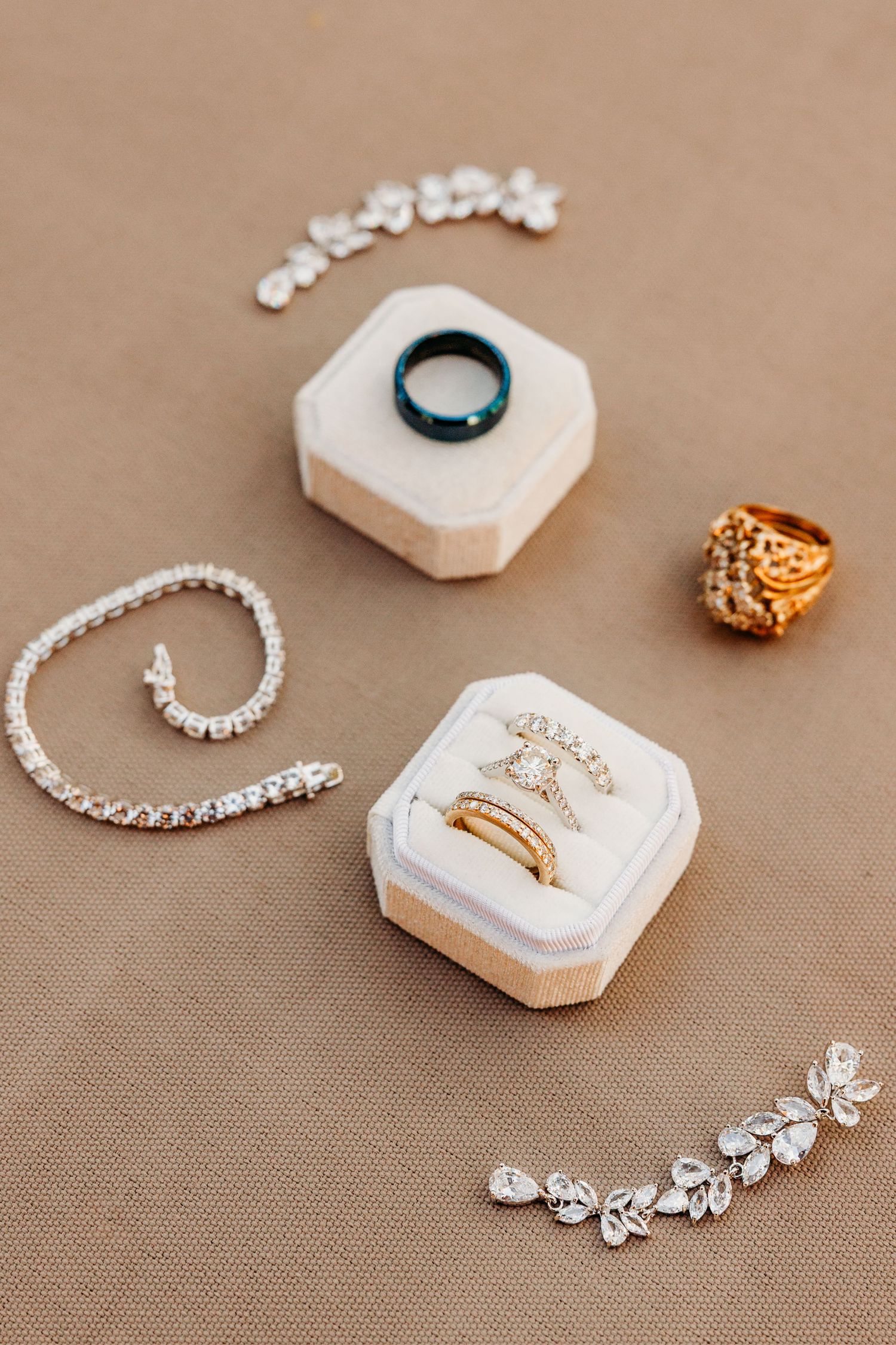 Elegant jewelry display featuring diamond bracelets and rings arranged on hexagonal beige stone holders against neutral background.