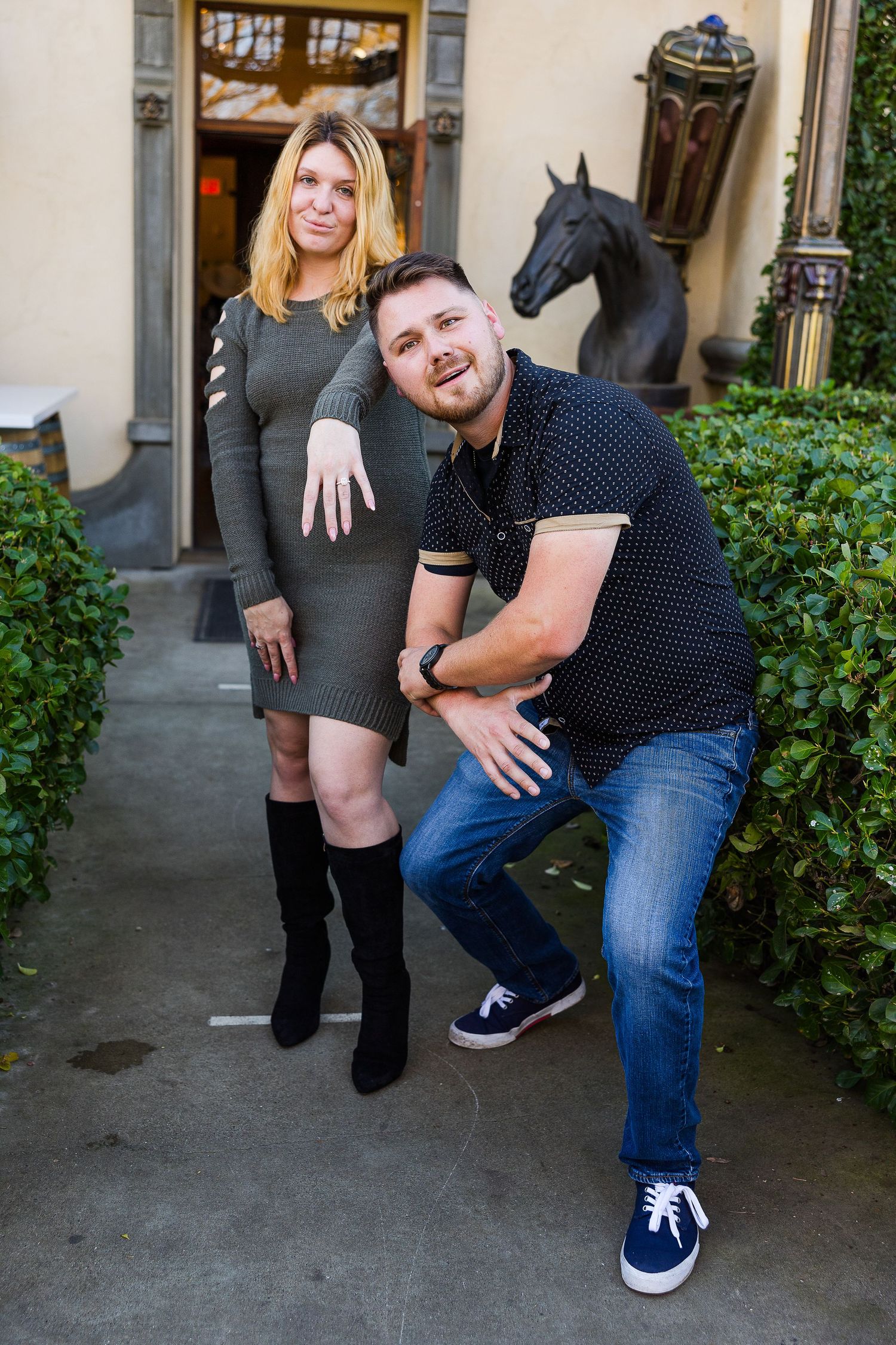Fun engagement photo with decorative horse statue in background.
