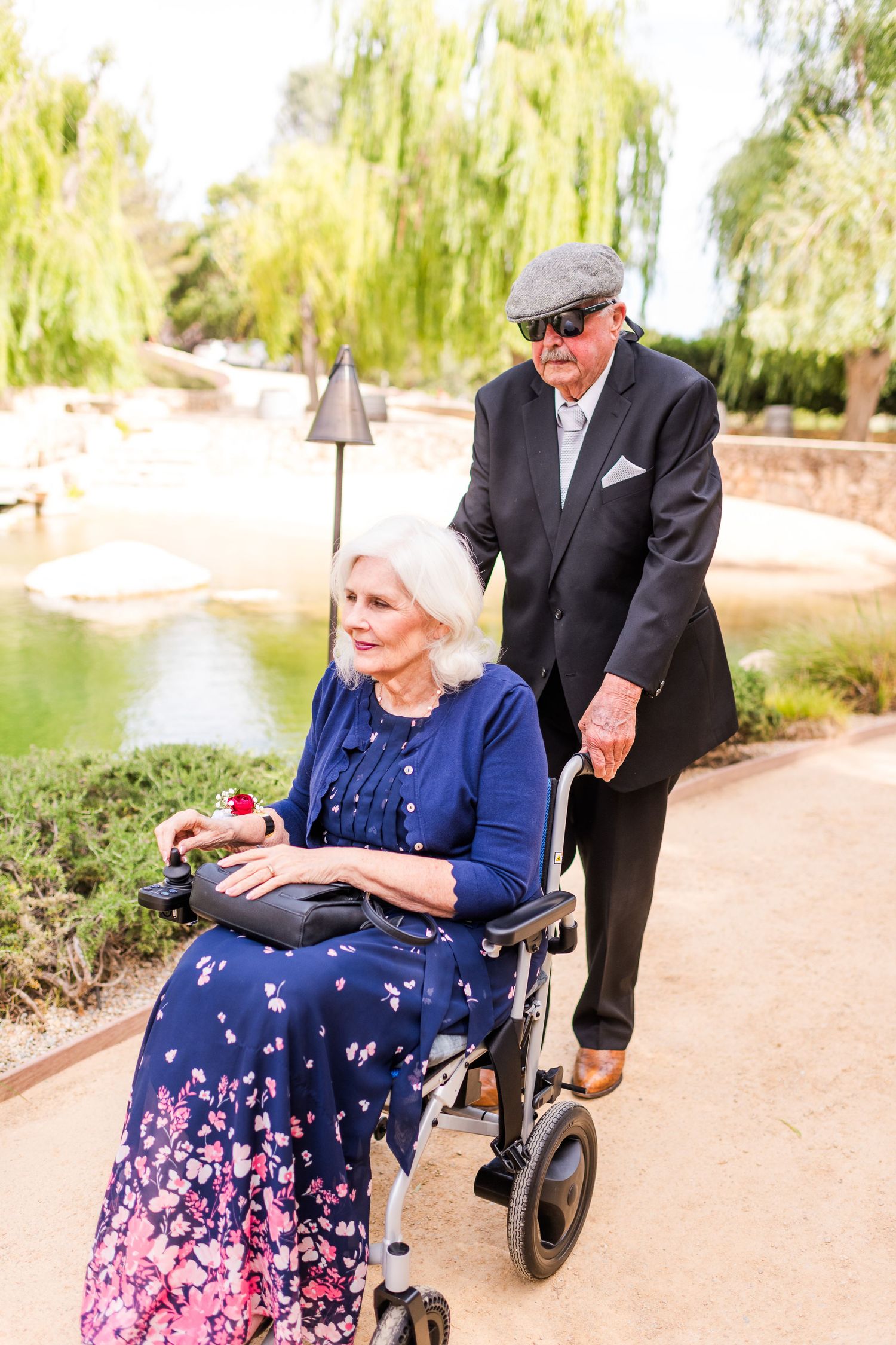 Two people enjoying a peaceful moment together in a garden setting with weeping willows.