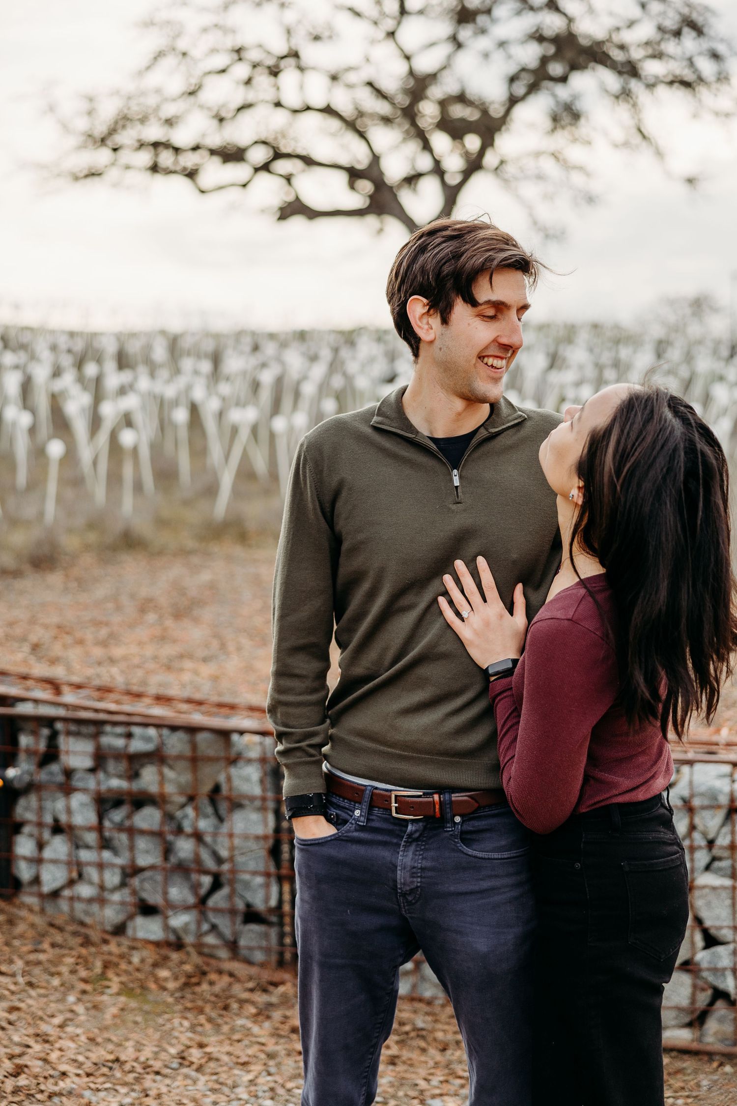 A couple shares a romantic moment together on fallen autumn leaves in a park setting.