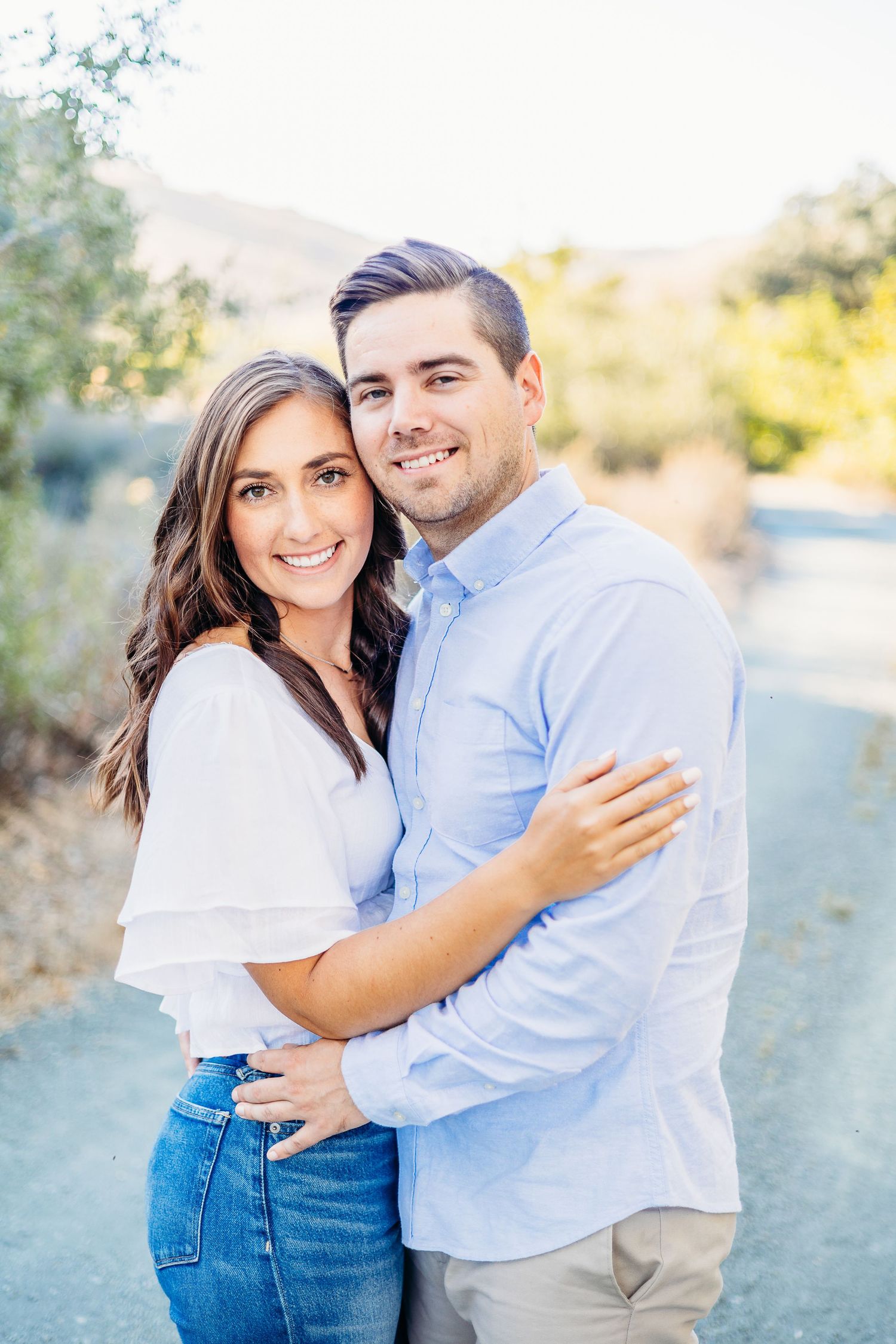 A couple in coordinated blue and white outfits embracing outdoors on a sunny day.