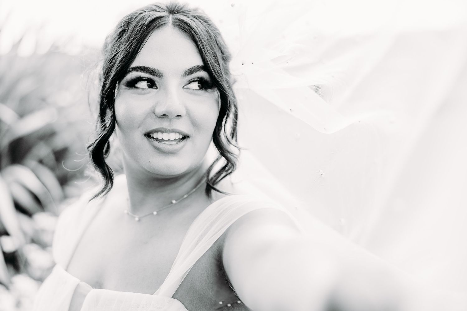 Black and white portrait shot of bride with curled hair and veil.