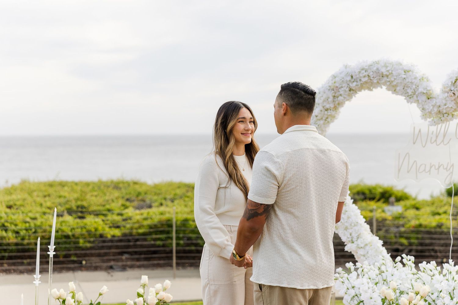 Romantic outdoor wedding ceremony on a lush green lawn with white chairs and floral arrangements.