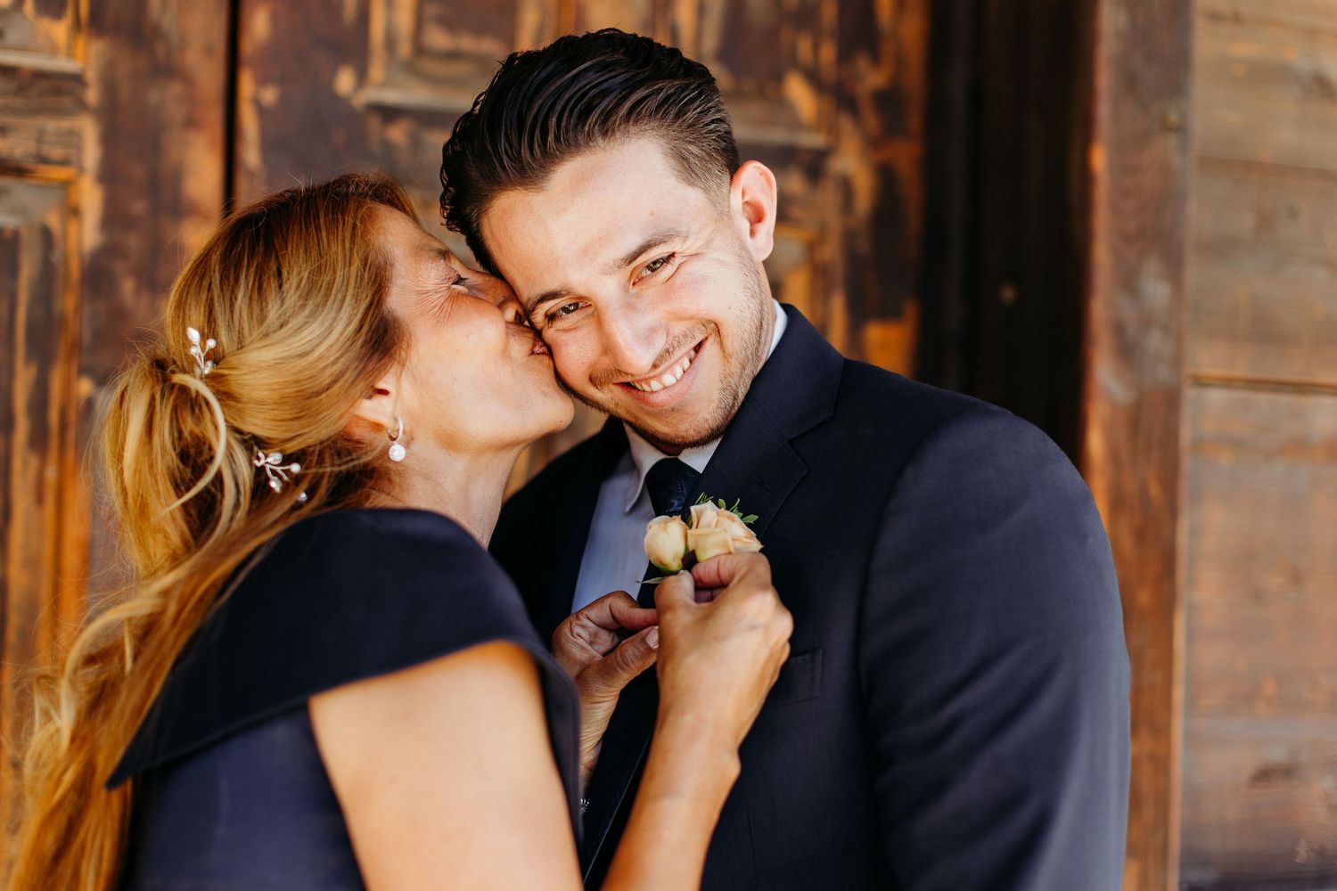 A romantic couple sharing an intimate moment in matching navy outfits with warm lighting in the background.